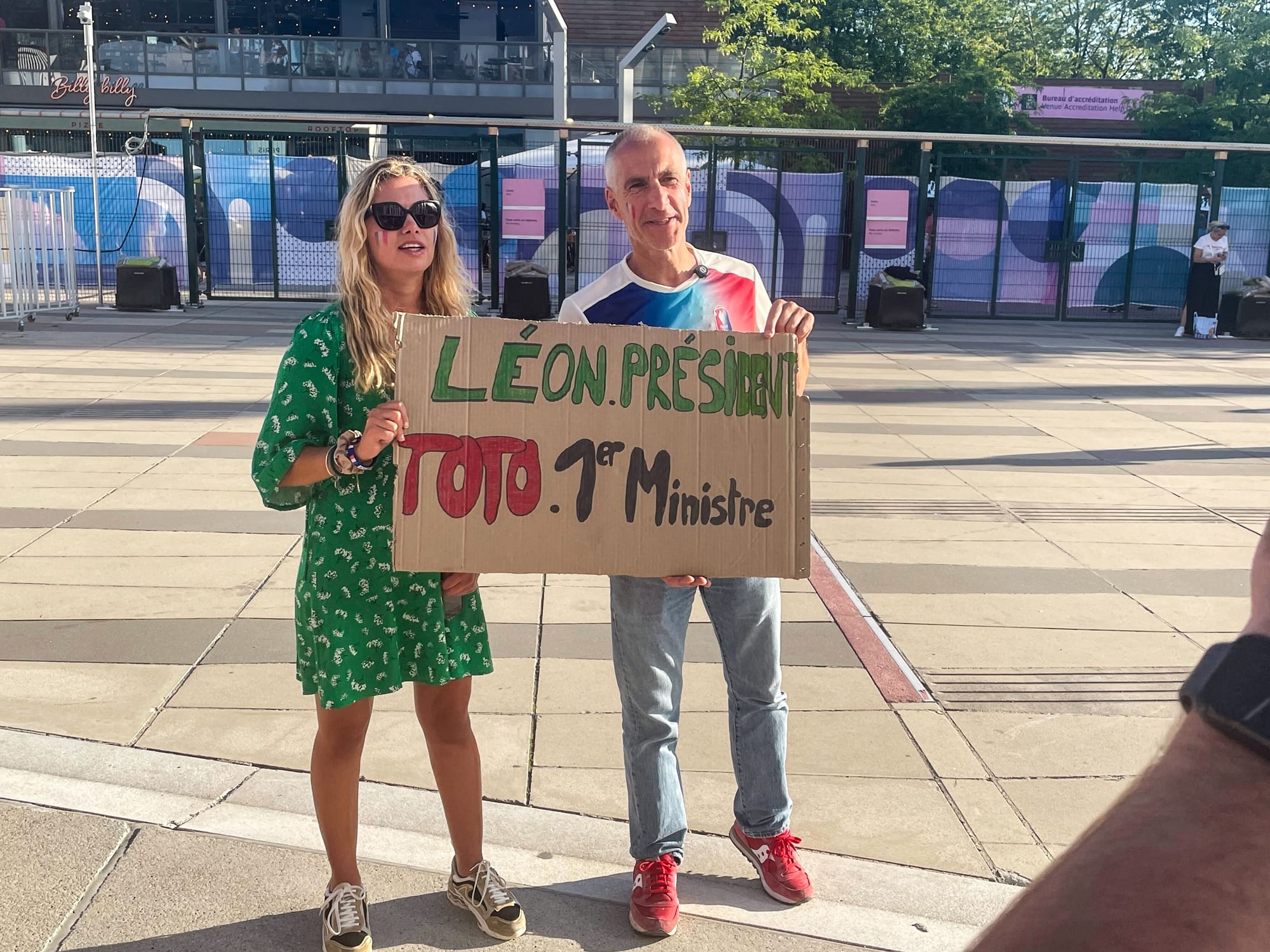 Two people hold a sign that reads: "Leon President Toto 1er Ministre"