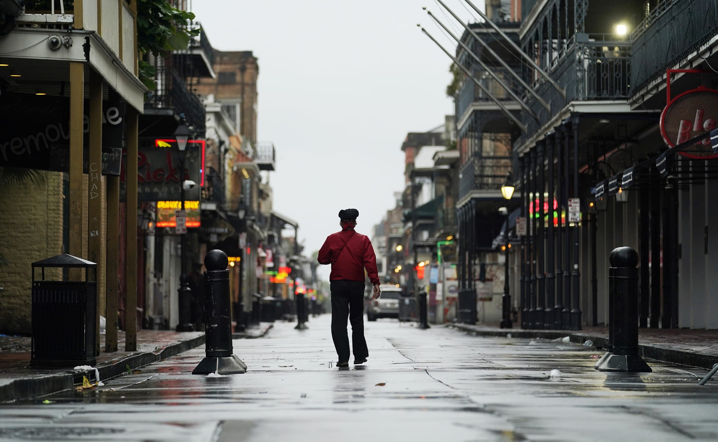 A man walks down a mostly deserted Bourbon Street in the French Quarter as the early effects of Hurricane Ida are felt on Sunday in New Orleans.