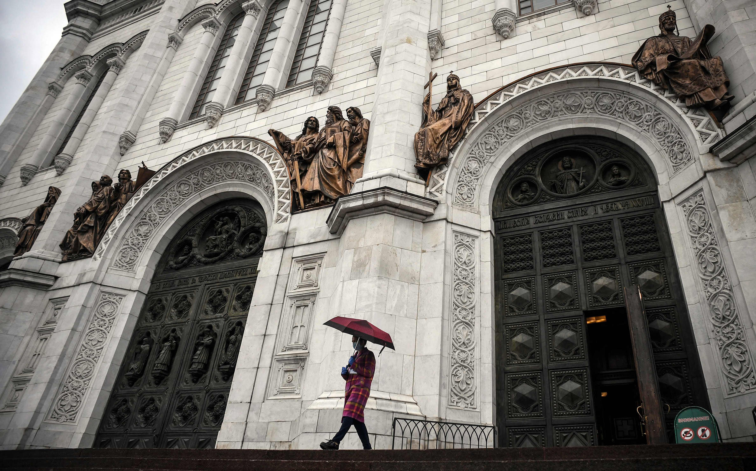 Image: A woman wearing a face mask comes out of Christ-the-Savior cathedral, the main Russian Orthodox church in central Moscow