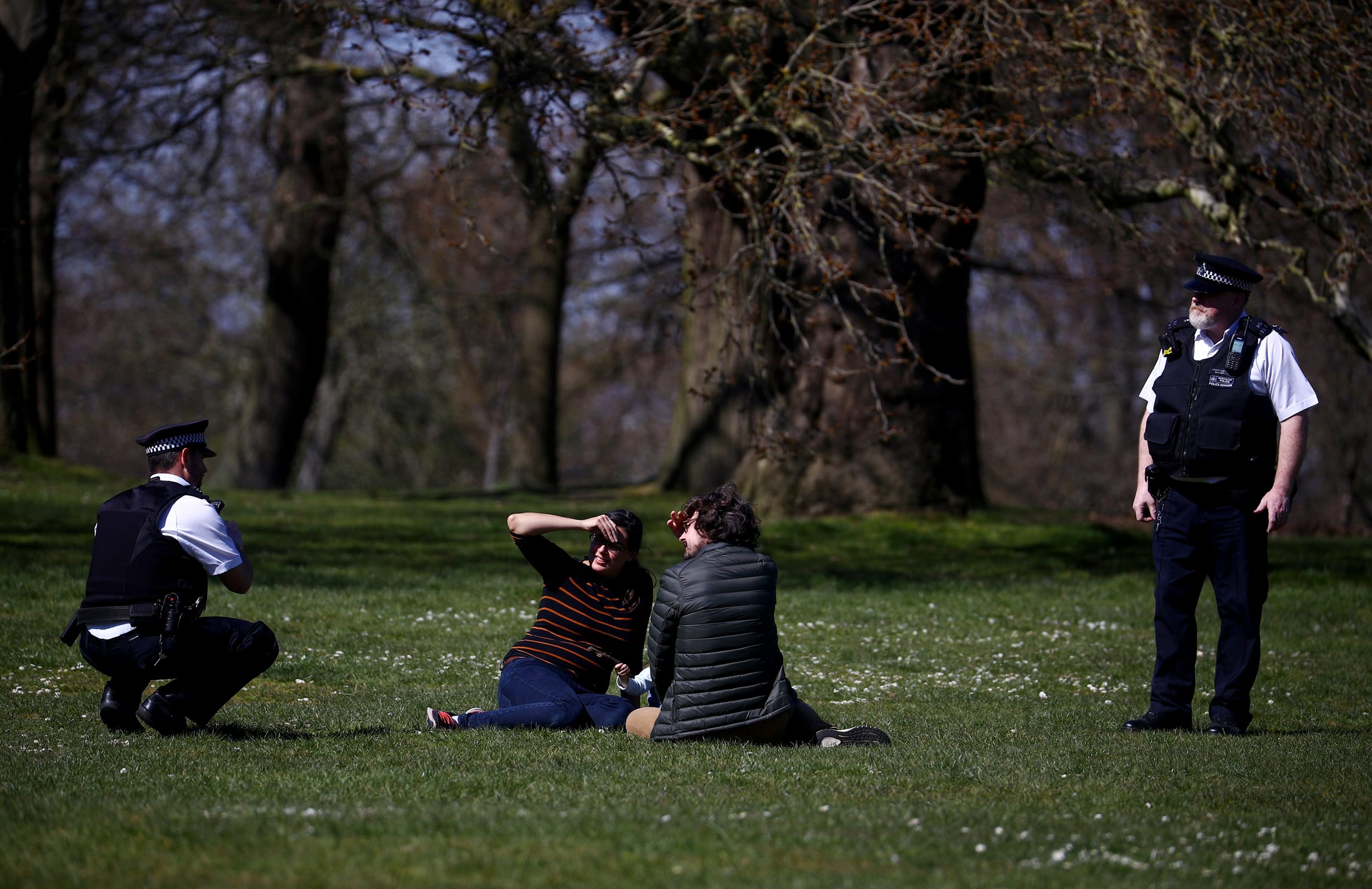 Image: Police officers speak with people at Greenwich Park in London on April 4, 2020.