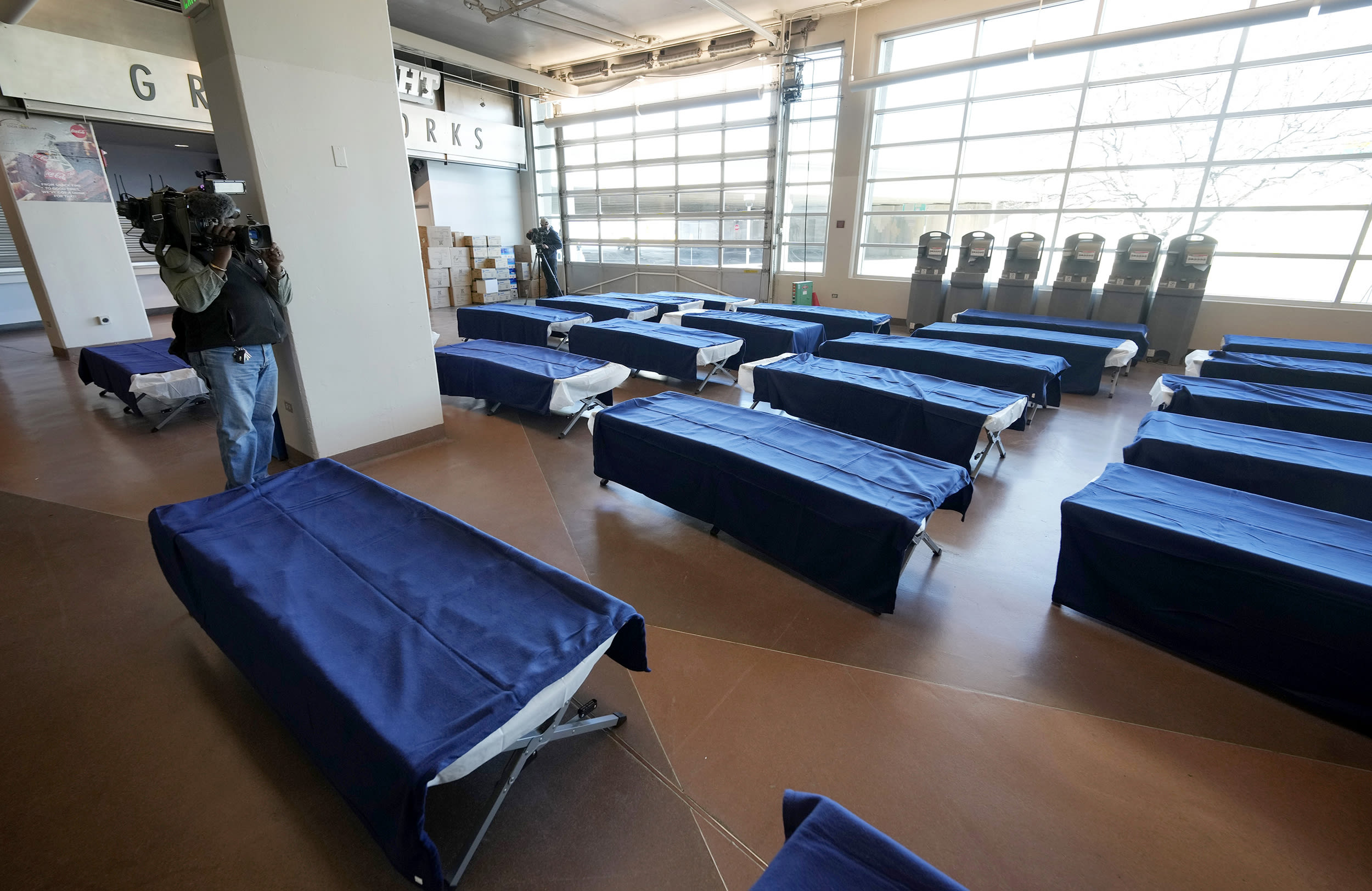 Lines of cots for people seeking refuge from the intense cold front sweeping over the intermountain West fill the walkways in the Denver Coliseum Wednesday, Dec. 21, 2022, in Denver. The home of the National Western Stock Show and Rodeo will be serving as a warming center until the severe weather abates. (AP Photo/David Zalubowski)