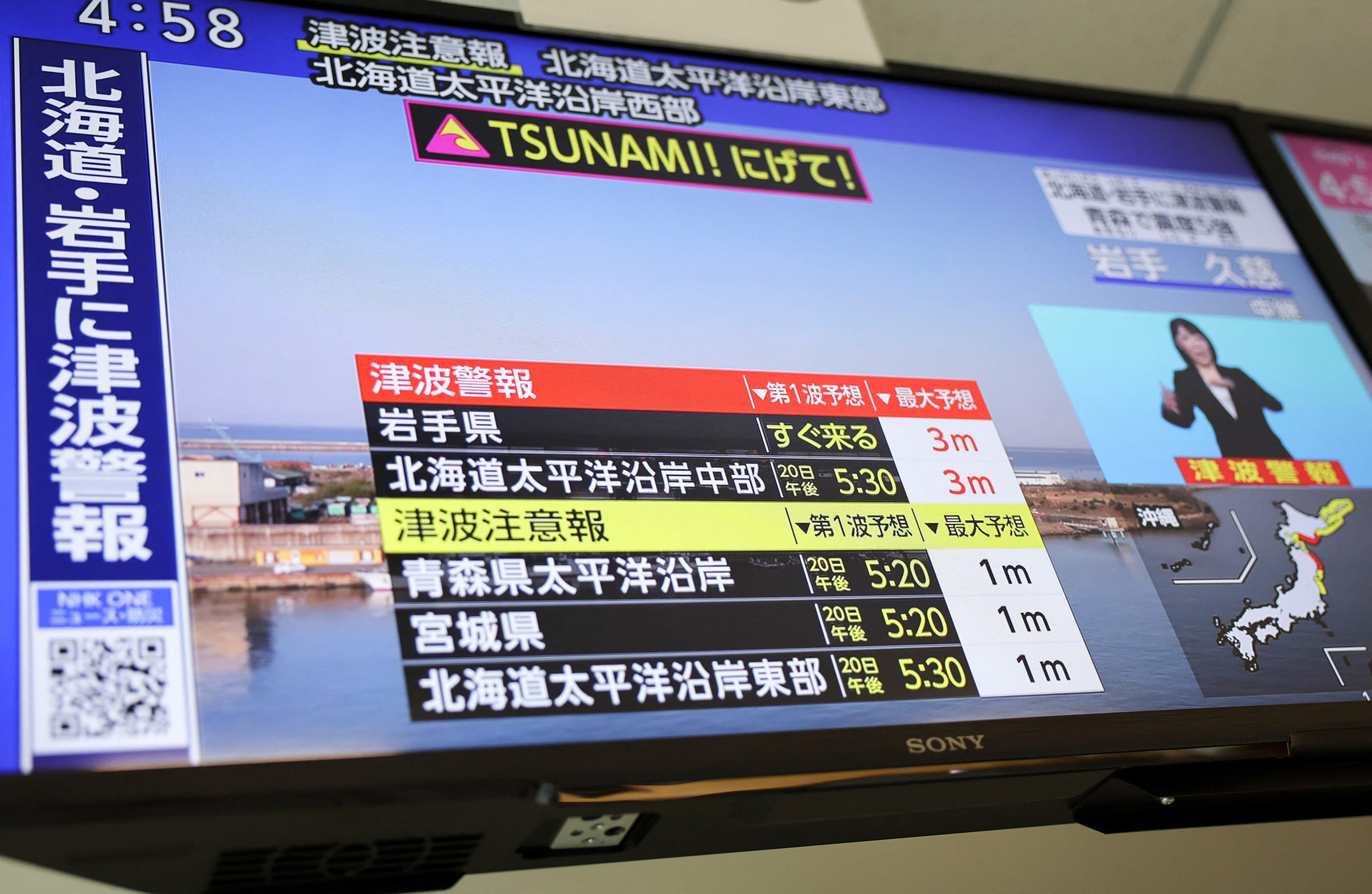 A television screen shows a news report on Japan Meteorological Agency's tsunami warning after an earthquake struck off the northeastern coast of Japan, in Tokyo
