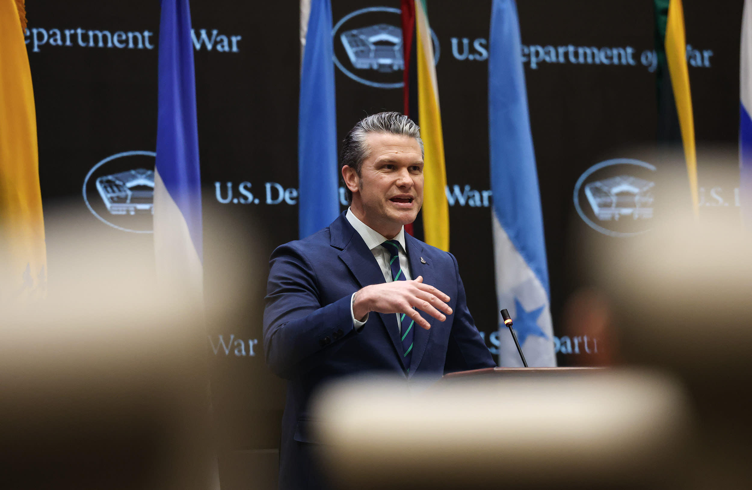 Pete Hegseth speaking in front of a backdrop that reads U.S. DEPARTMENT OF WAR.