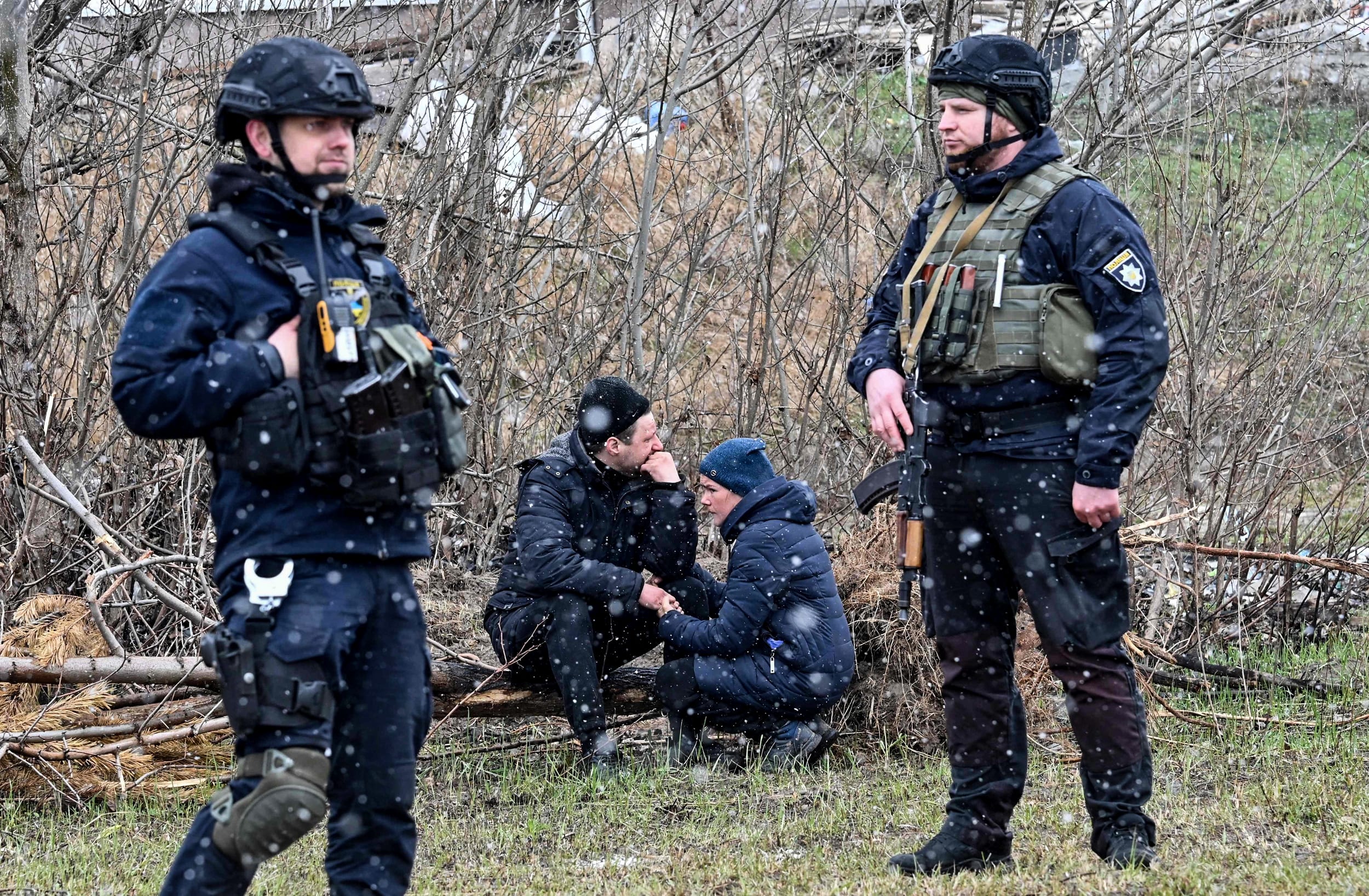 People react as they gather close to a mass grave in the town of Bucha, Kyiv oblast, Ukraine, on April 3, 2022.