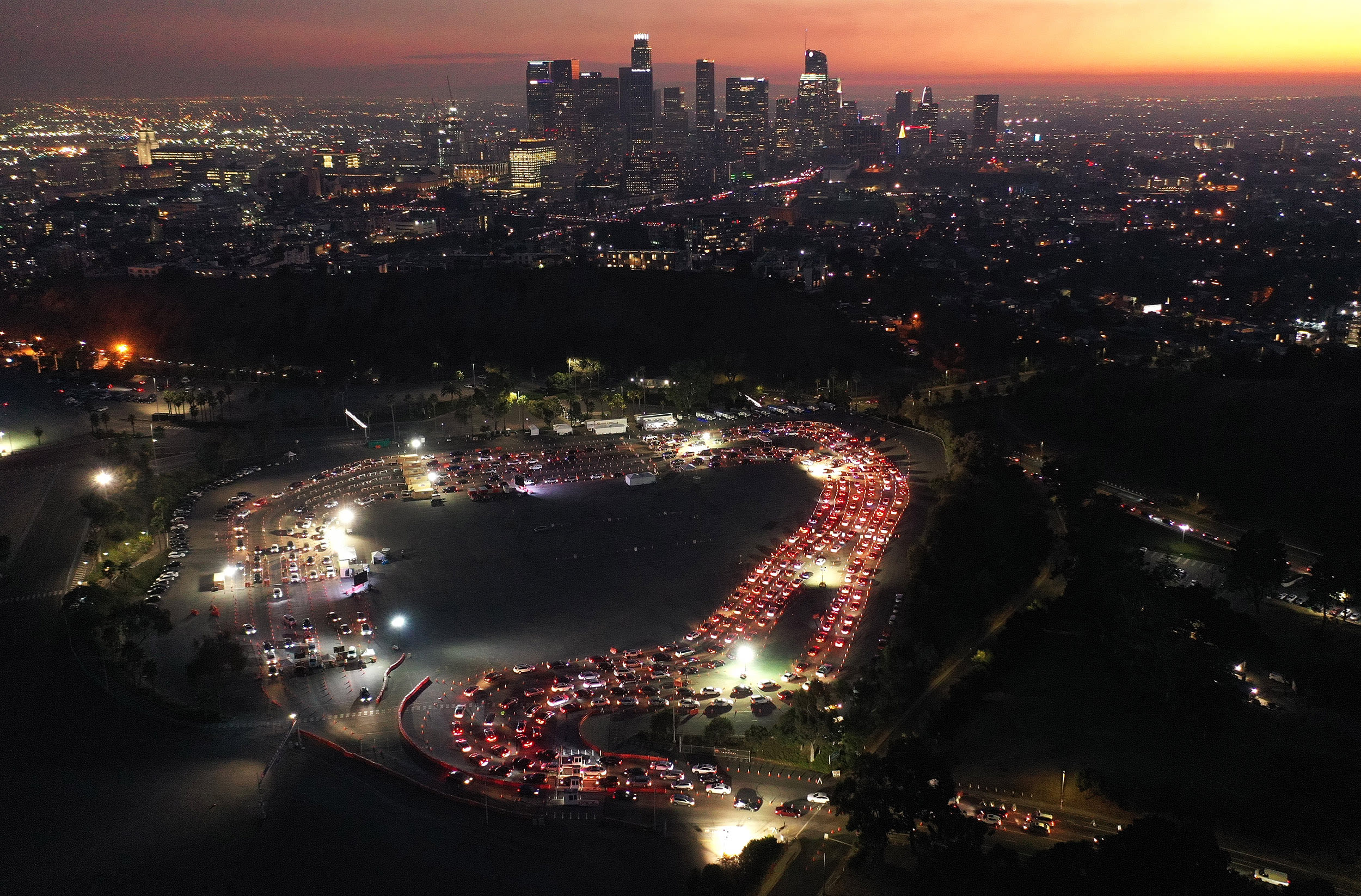 Image: Cars are lined up at Dodger Stadium for COVID-19 testing as dusk falls over downtown on Dec. 2, 2020 in Los Angeles.