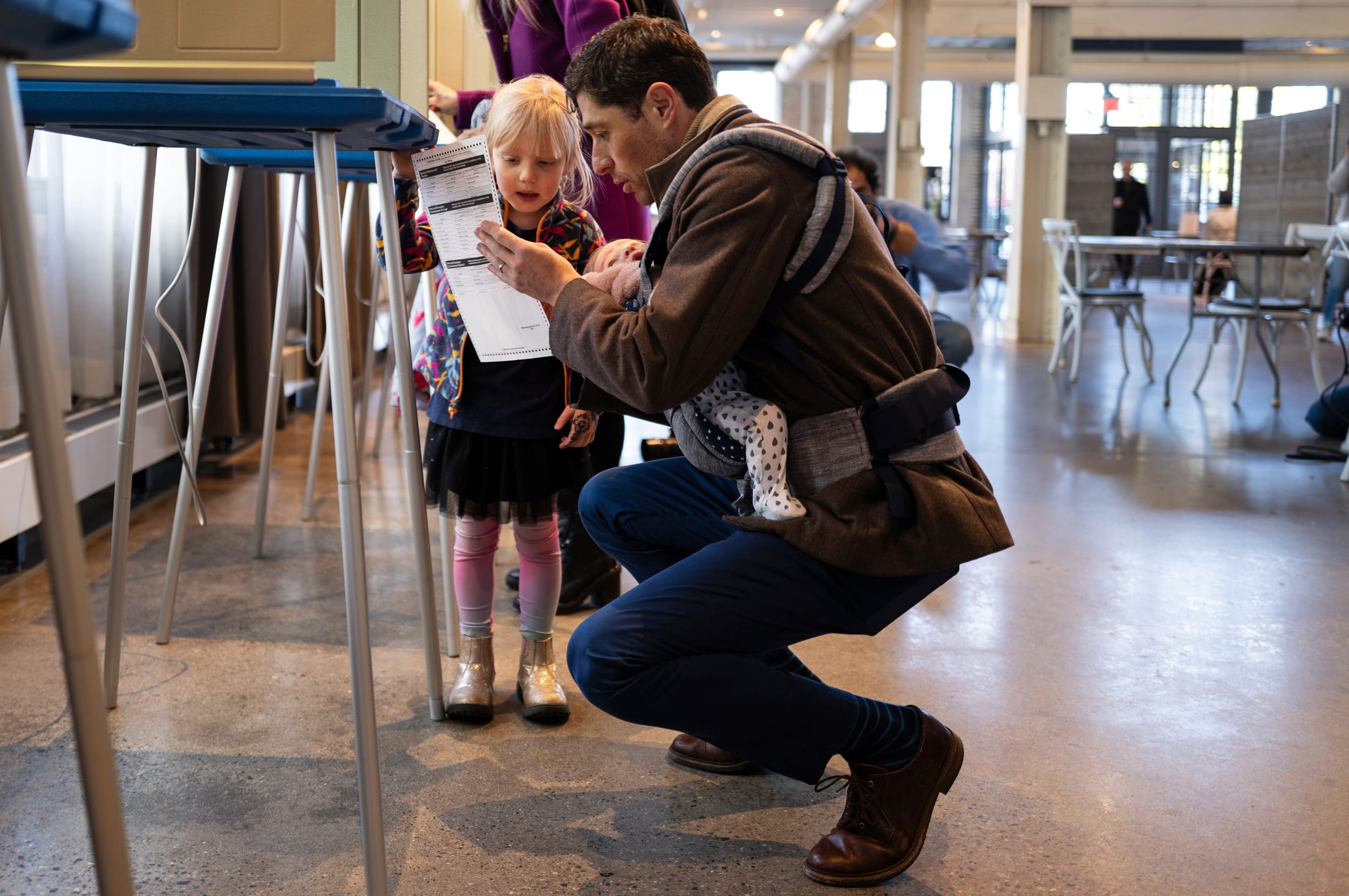 Minneapolis Mayor Jacob Frey fills out his ballot with his daughter Freida Frey as he holds his child Estelle Frey at a polling place on Election Day on Nov. 4, 2025.