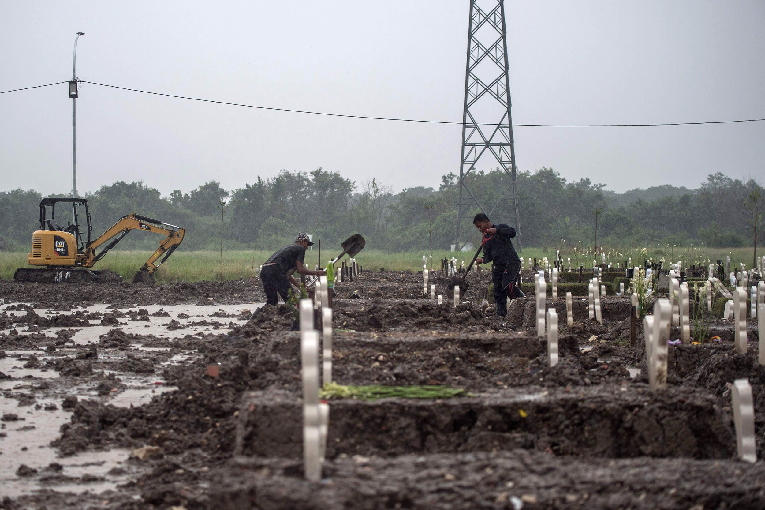 Image: Gravediggers bury a Covid-19 coronavirus victim amid pouring rain at Keputih cemetery in Surabaya, Indonesia