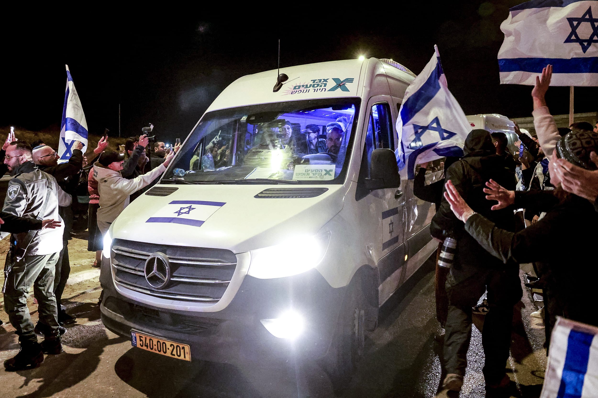 Image: Newly released Israeli hostages sit among soldiers as they arrive inside a van