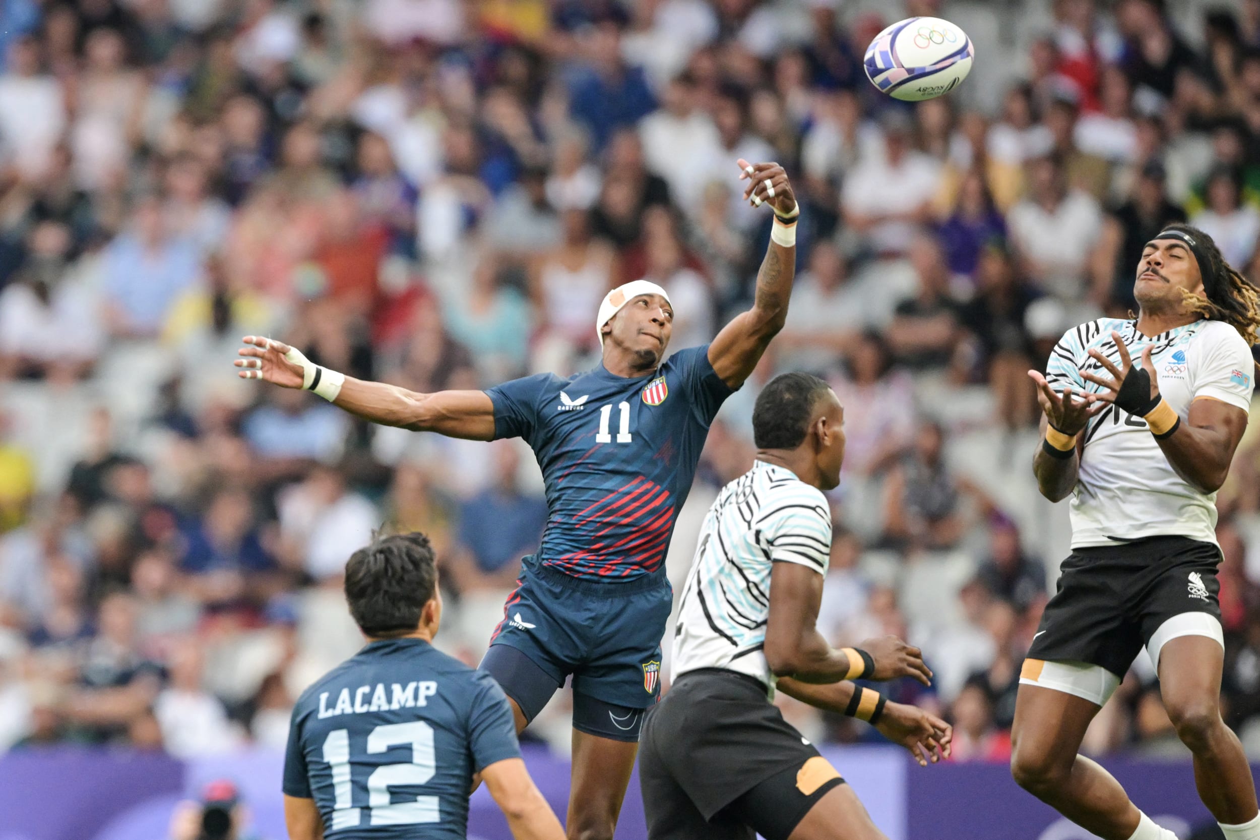Team USA's Perry Baker, center, and Fiji's Selesitino Ravutaumada jump for the ball 