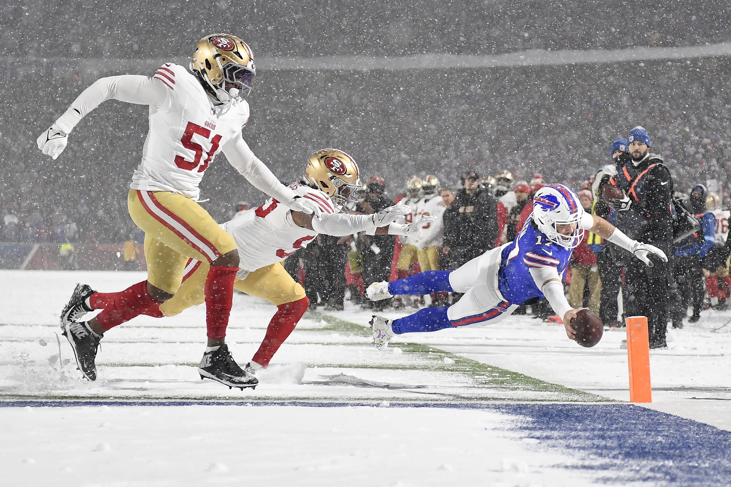 Buffalo Bills quarterback Josh Allen dives toward the end zone to score past San Francisco 49ers defensive end Robert Beal Jr. and linebacker Dee Winters.