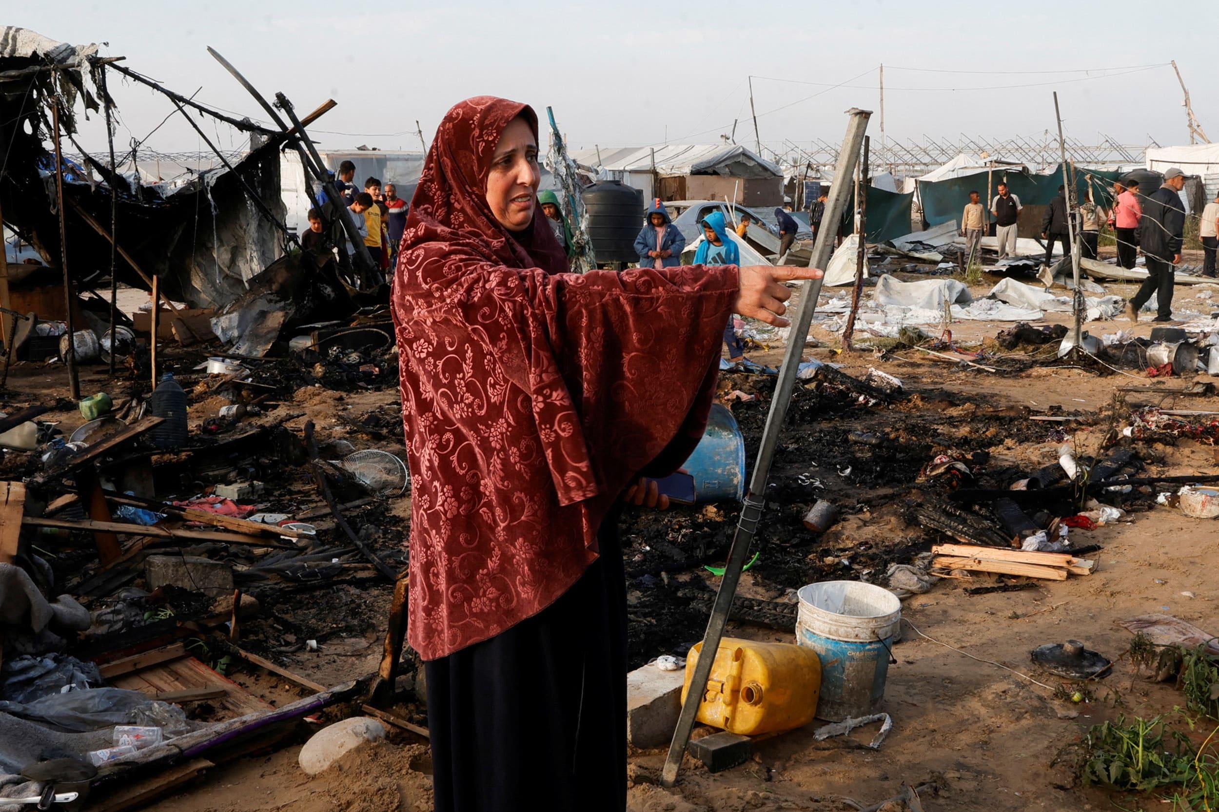 Palestinian woman gestures as people inspect the site of an Israeli strike on a tent camp housing displaced people, in Al-Mawasi area, in Khan Younis in the southern Gaza Strip