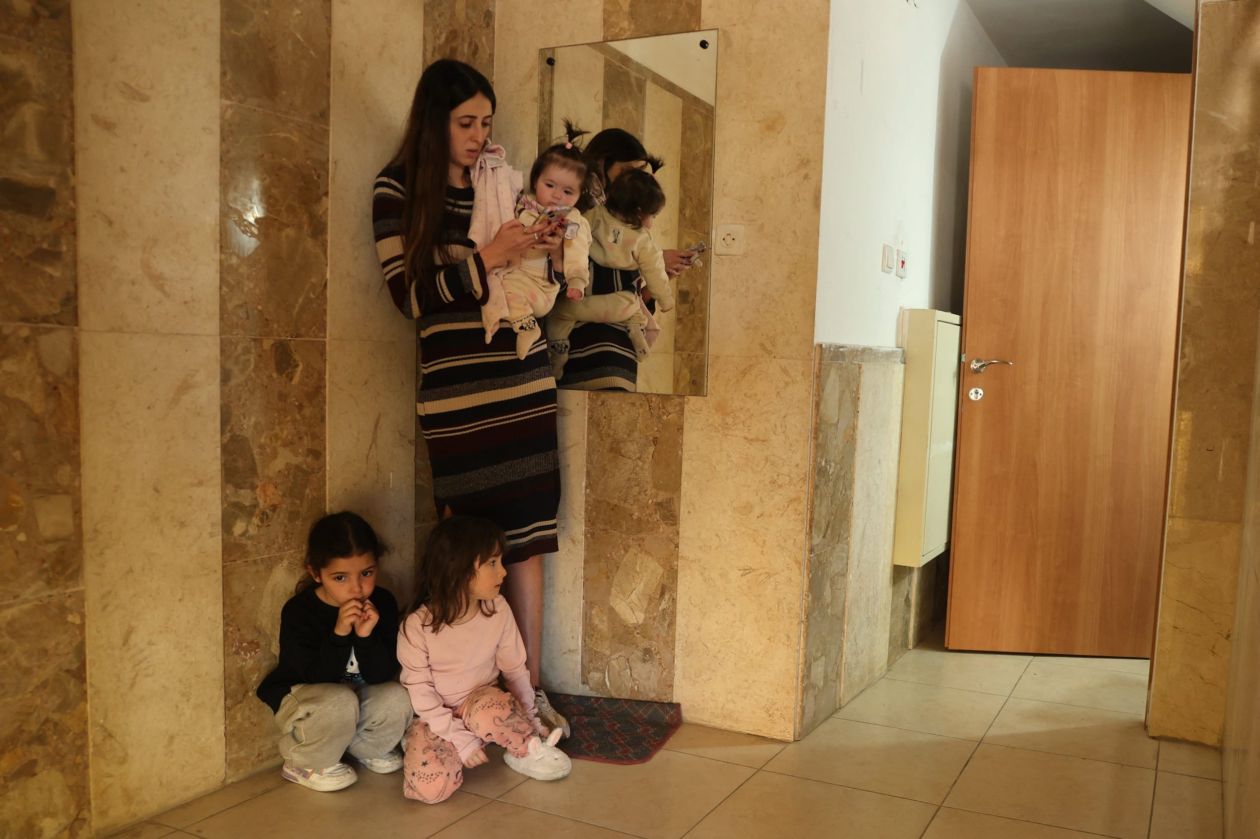 A family shelters as sirens sound, warning of a missile attack over Holon, on the outskirts of Tel Aviv, on March 17, 2026. 
