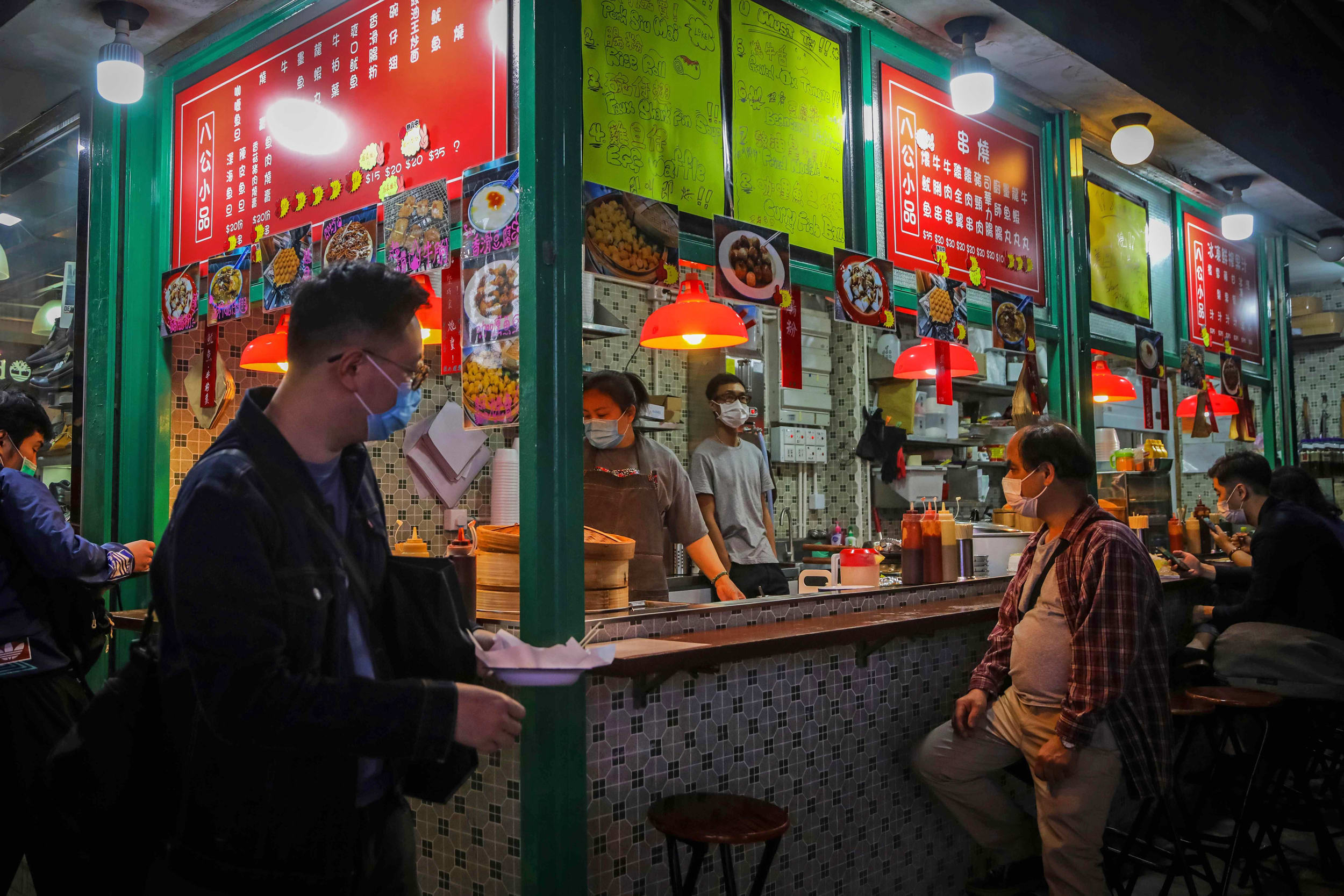 Customers wearing masks eat at a street stall during the evening rush hour in Hong Kong on March 4, 2020.