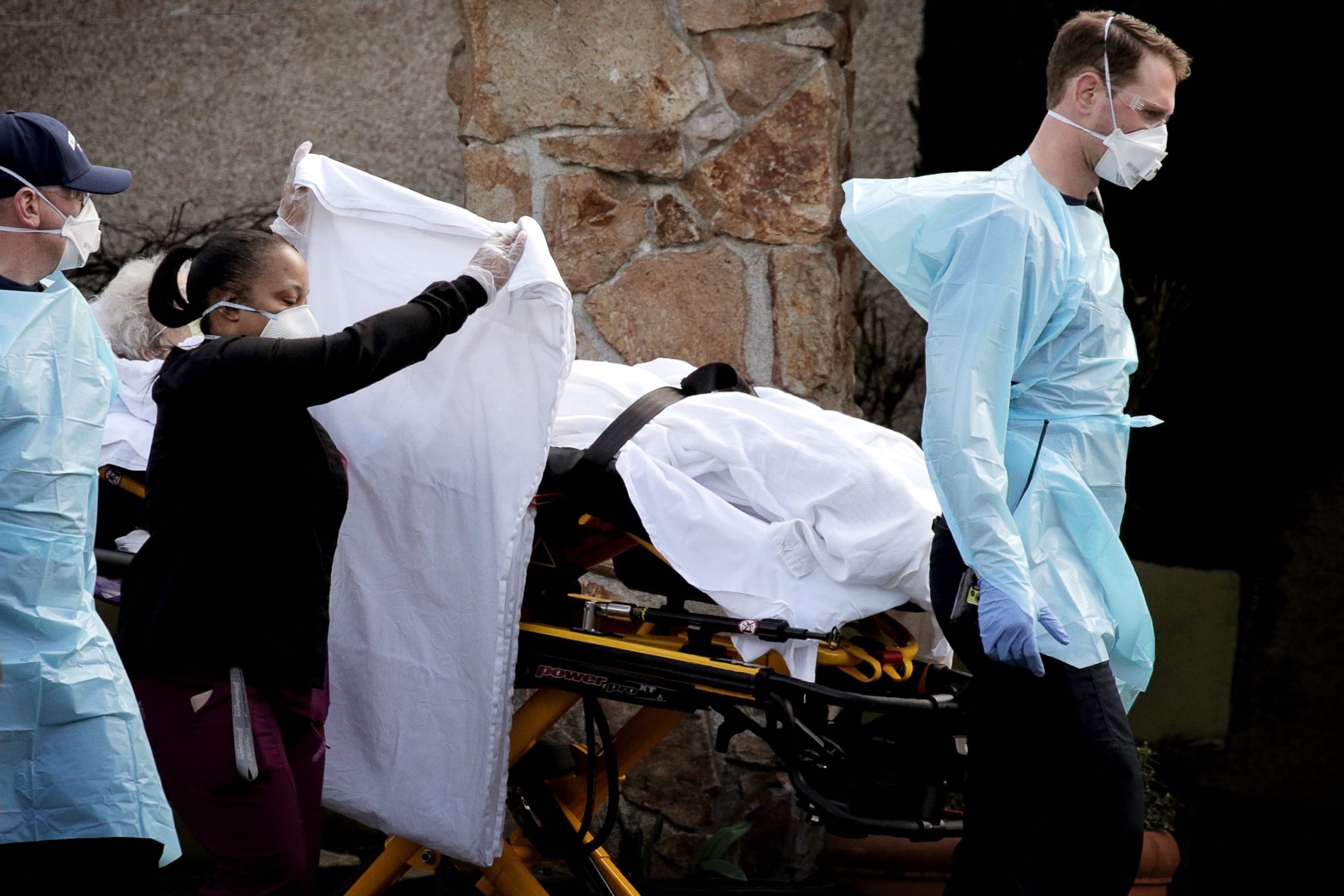 Image: Medics transport a patient to an ambulance from the Life Care Center of Kirkland, a long-term care facility linked to several confirmed coronavirus cases, in Kirkland, Wash., on March 7, 2020.
