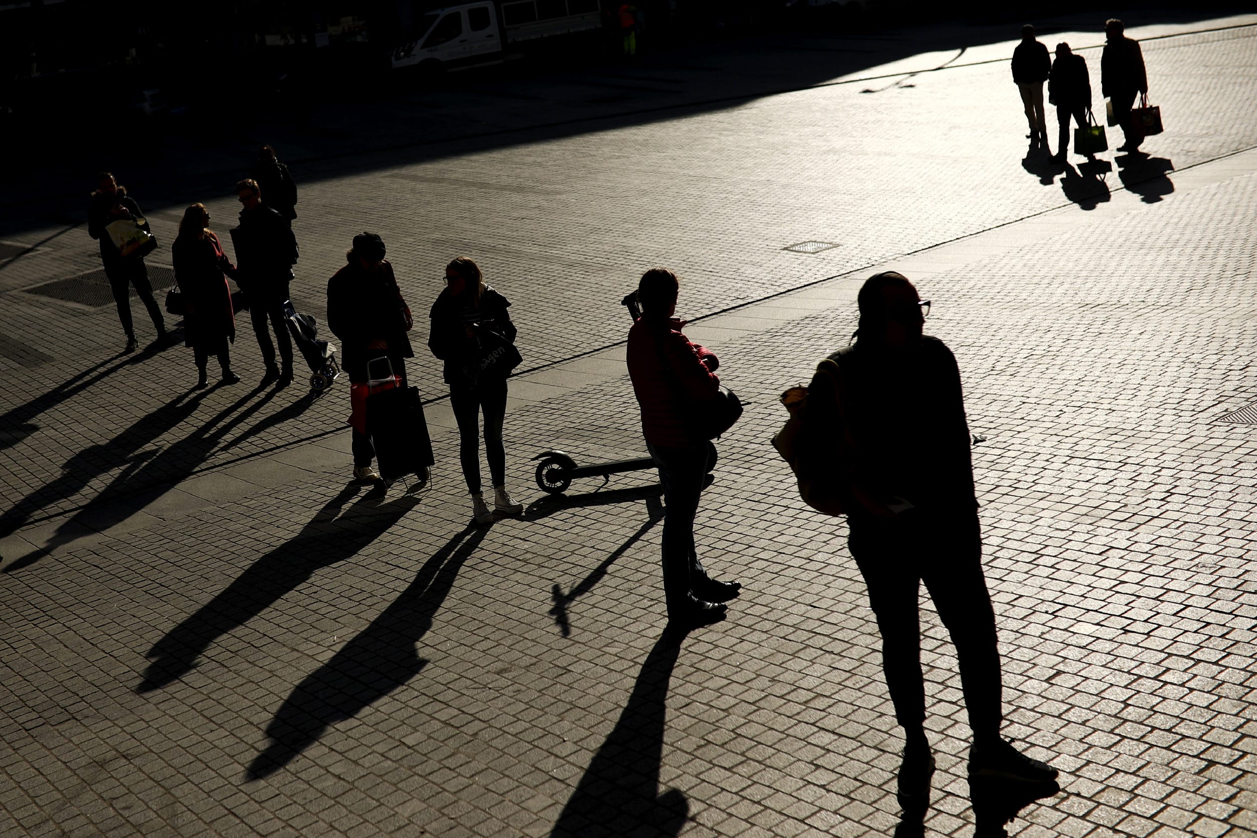 Image: People stand apart while waiting to enter a supermarket in Brussels on March 18, 2020.