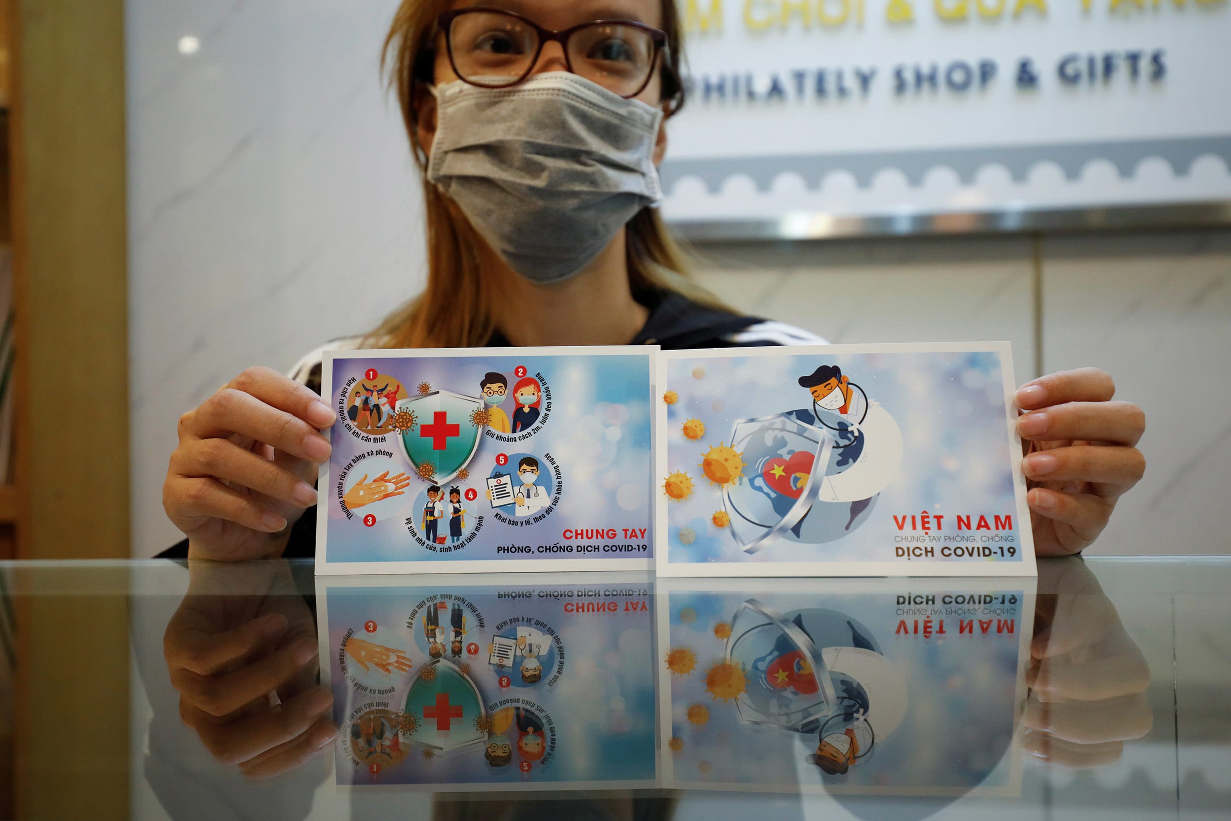 Image: A stamp seller shows off special postcards with anti-coronavirus images in Hanoi, Vietnam March 31, 2020.