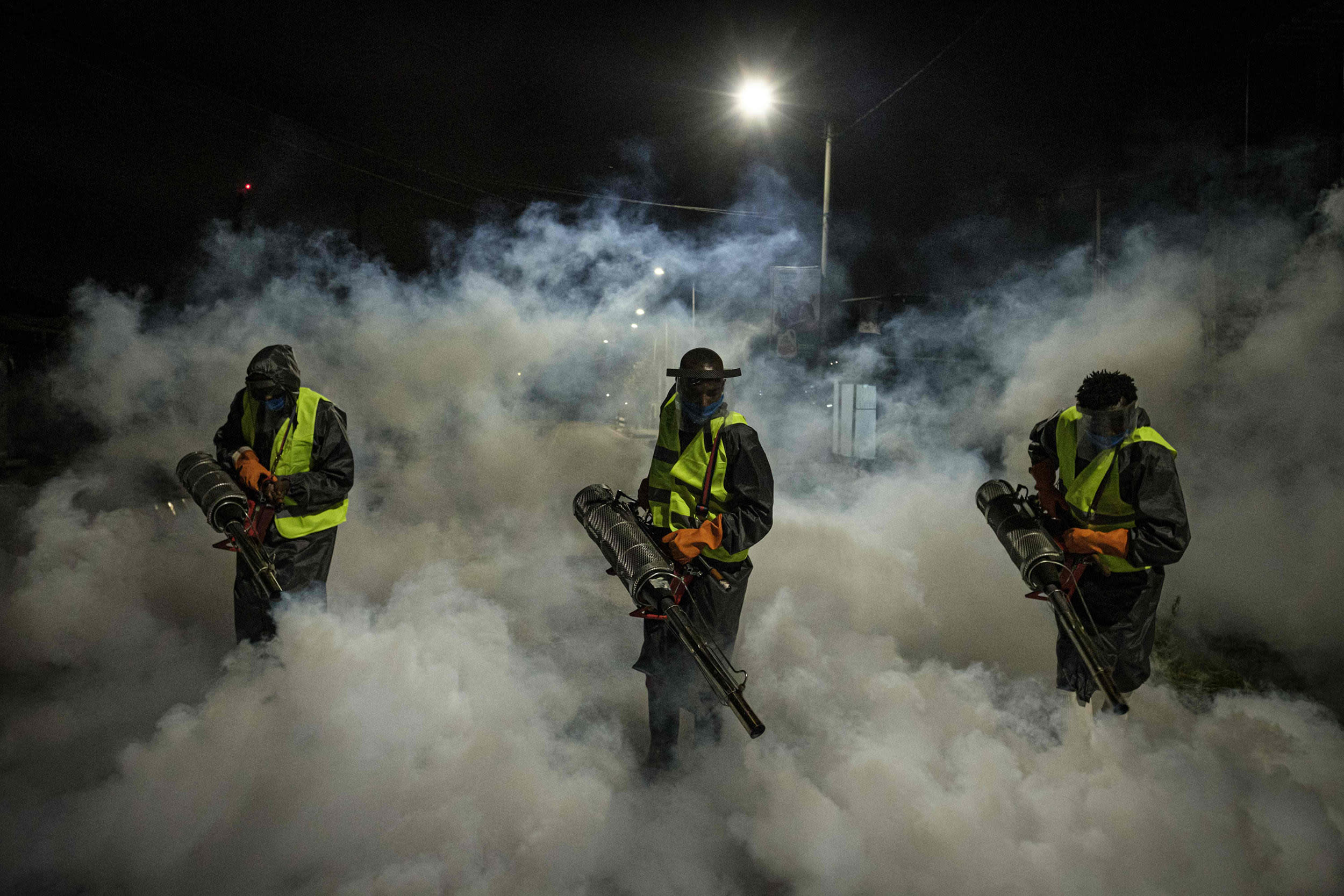 Image: Volunteers fumigate a street in a residential area of Nairobi to curb the spread of coronavirus on Monday.