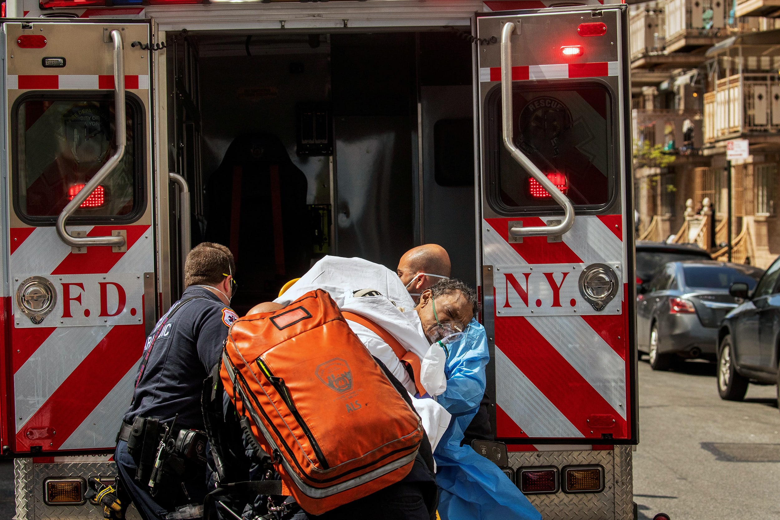 Image: New York City Fire Department and Emergency Medical Technicians lift a man after moving him from a nursing home into an ambulance