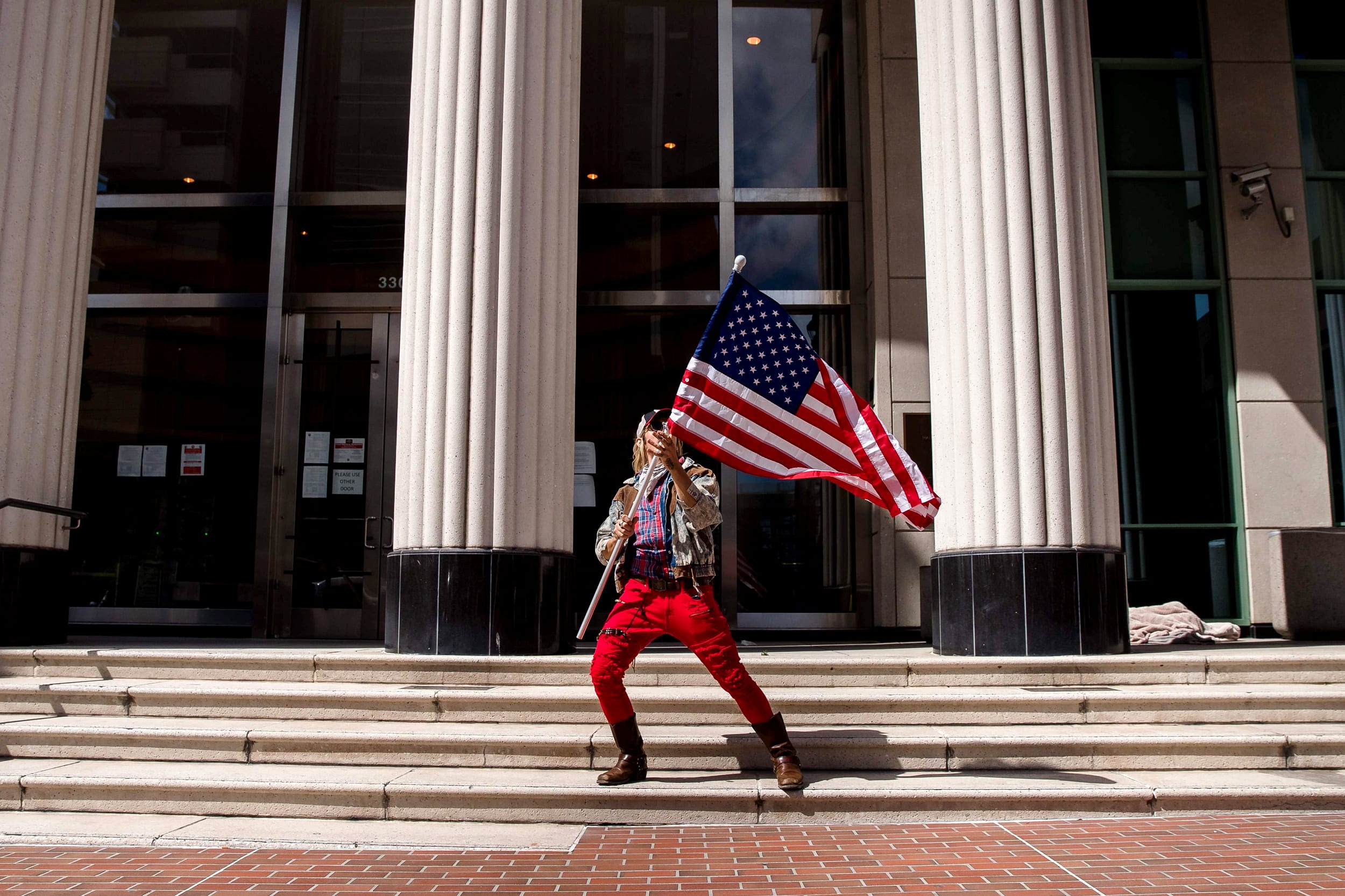 Image: A man waves an American flag during a rally against California's stay at home orders in San Diego on April 18, 2020.