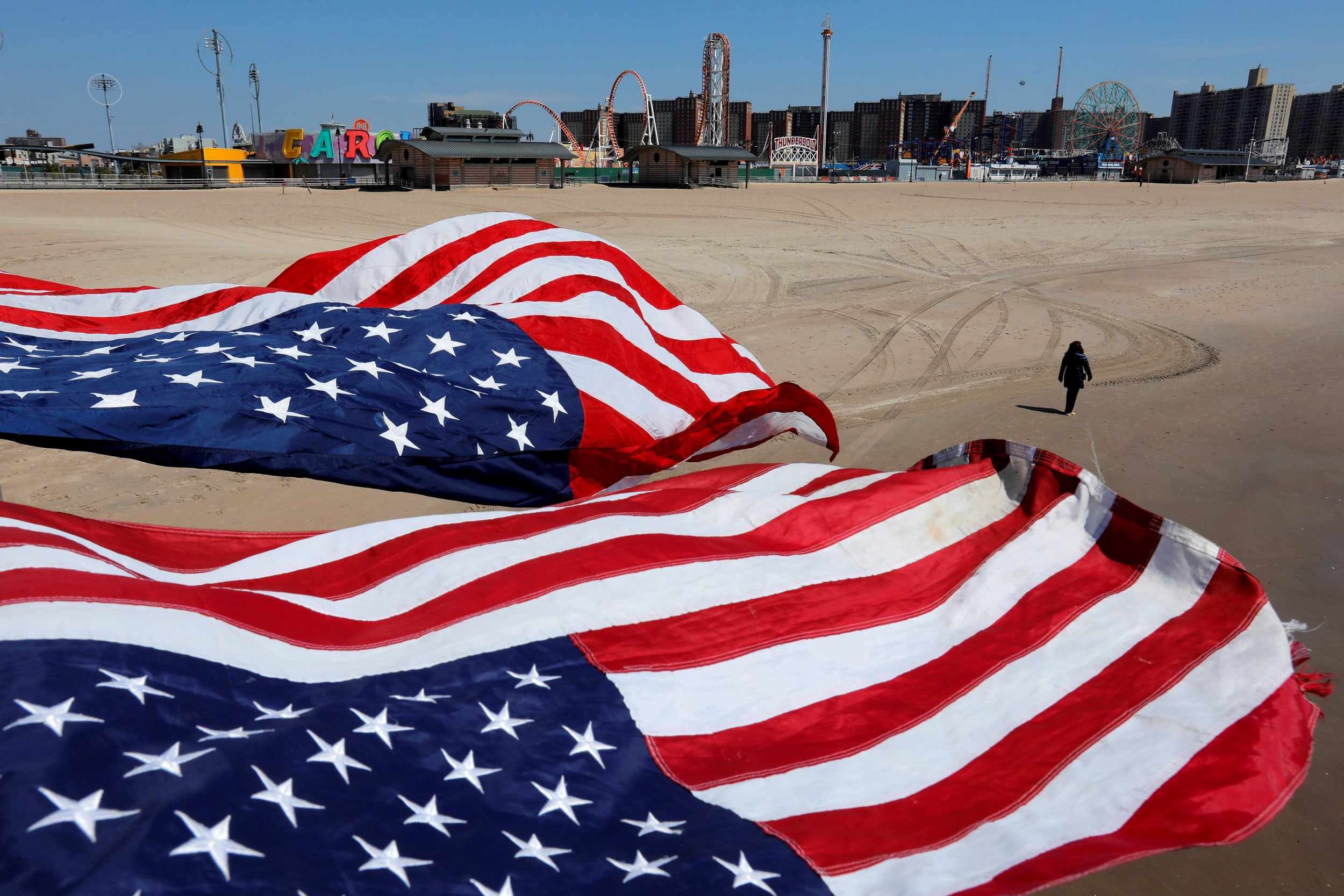 Image: A person walks along the sand at the empty Coney Island beach in Brooklyn, N.Y., on April 19, 2020.