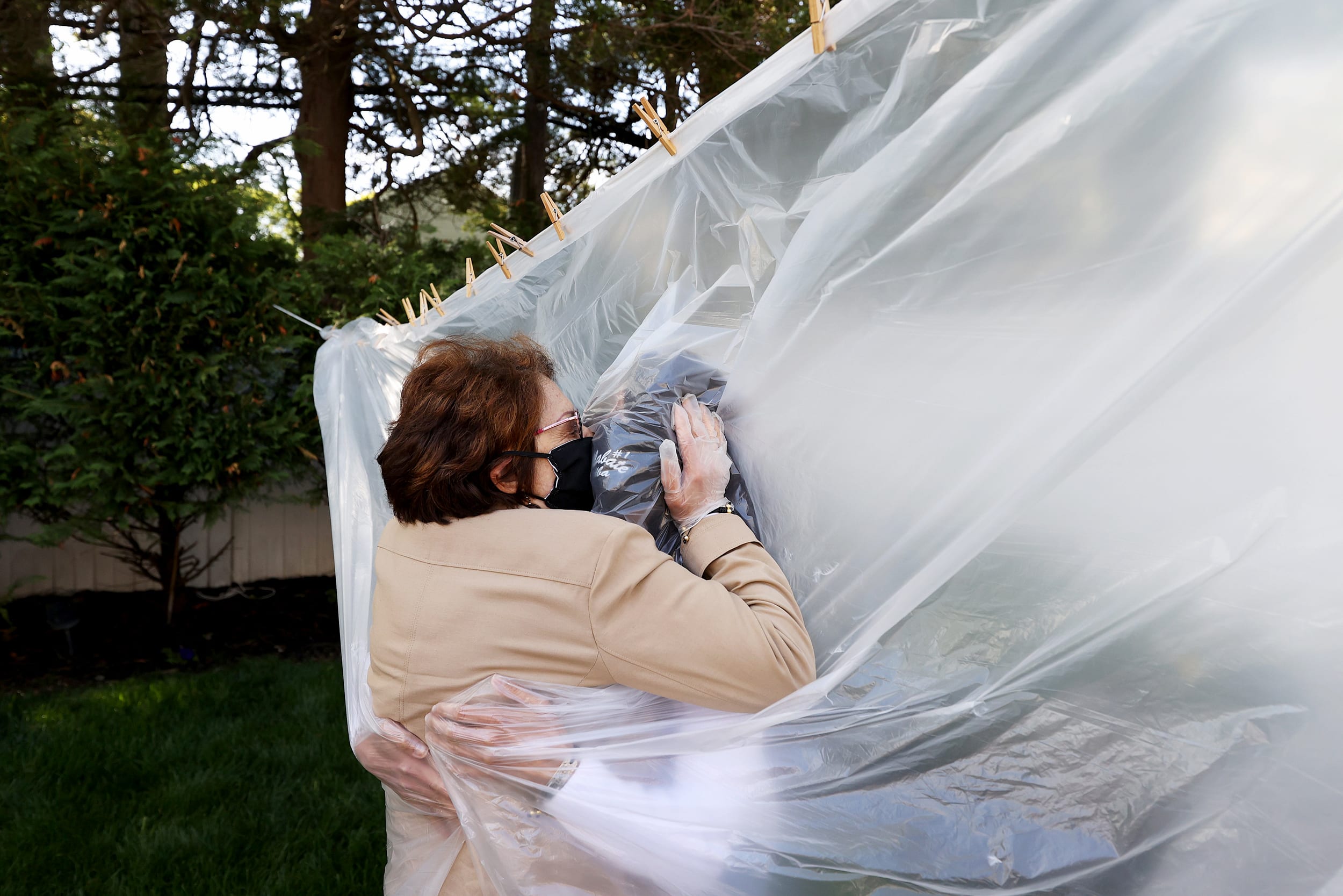 Image: Michelle Grant, right, hugs her mother, Mary Grace Sileo, through a plastic drop cloth hung up on a clothesline in Wantagh, N.Y., on May 24, 2020. It was the first time the mother and daughter had physical contact since lockdown measures began in l