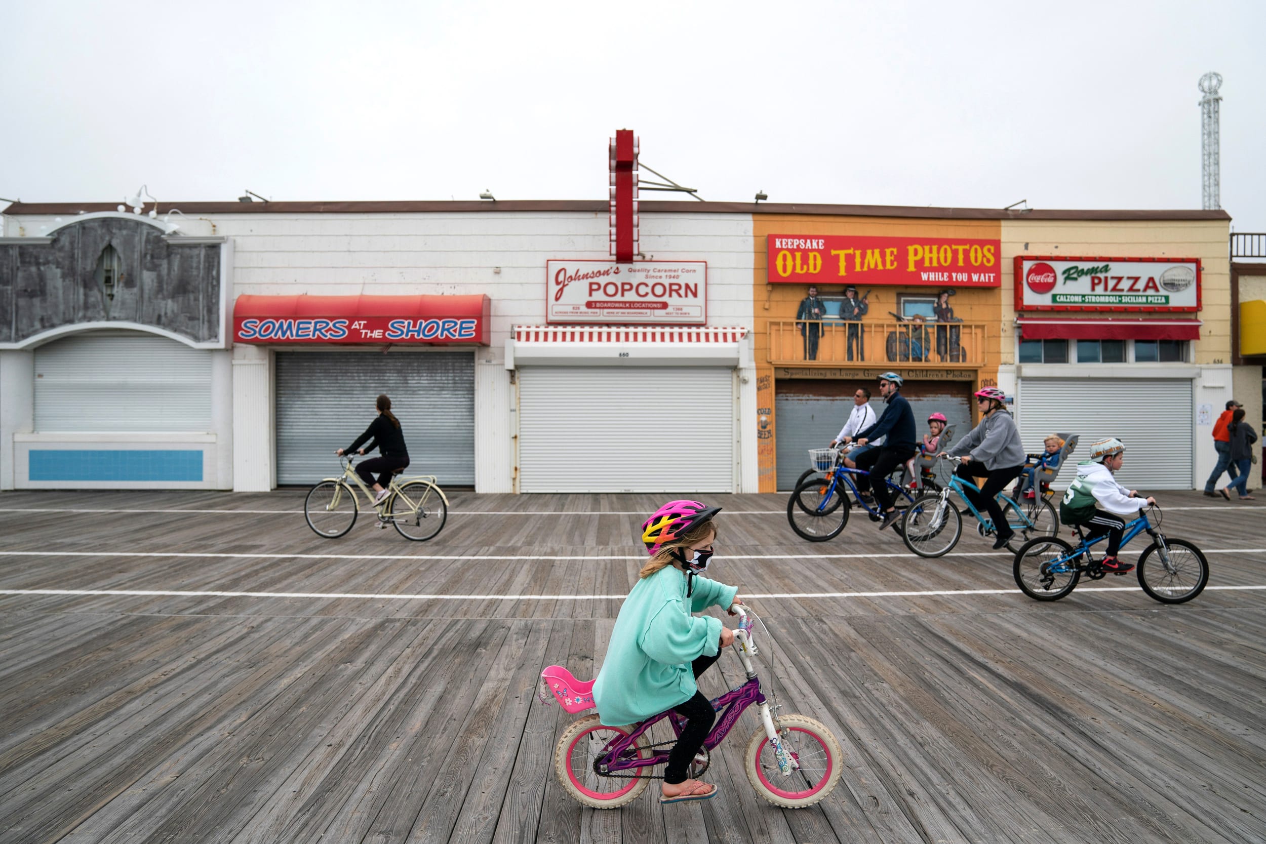 Image: People ride bicycles along the Ocean City boardwalk in N.J. on May 25, 2020.