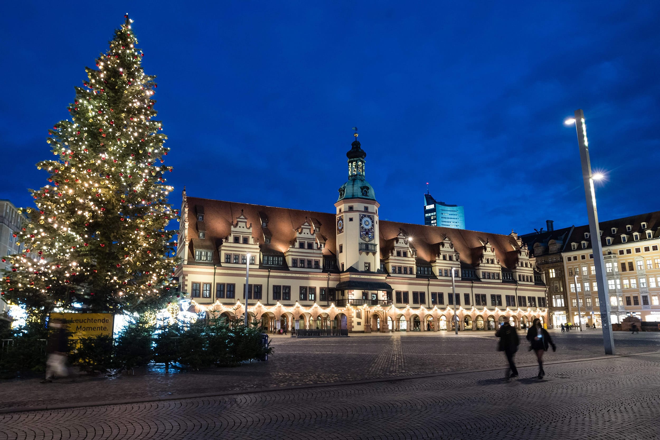 Image: People walk across the almost deserted market square with decorated Christmas tree in Leipzig, eastern Germany