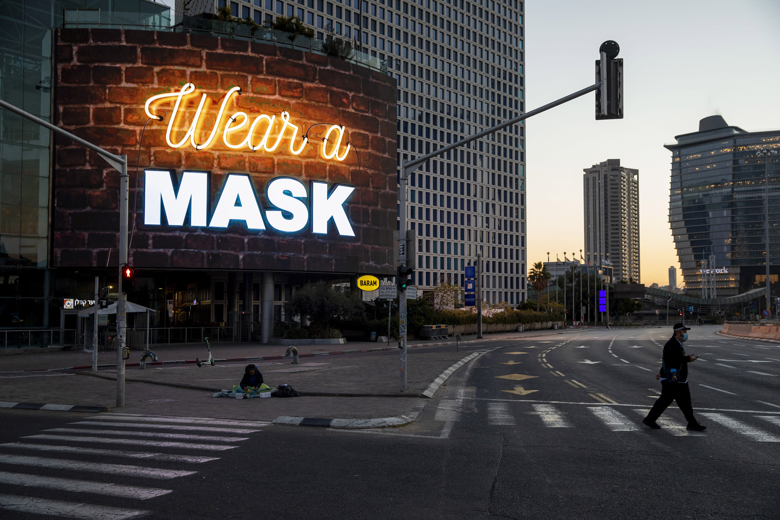 Image: A man crosses a road next to a billboard calling for people to wear masks during a nationwide lockdown following the government's measures to help stop the spread of the coronavirus in Tel Aviv, Israel,