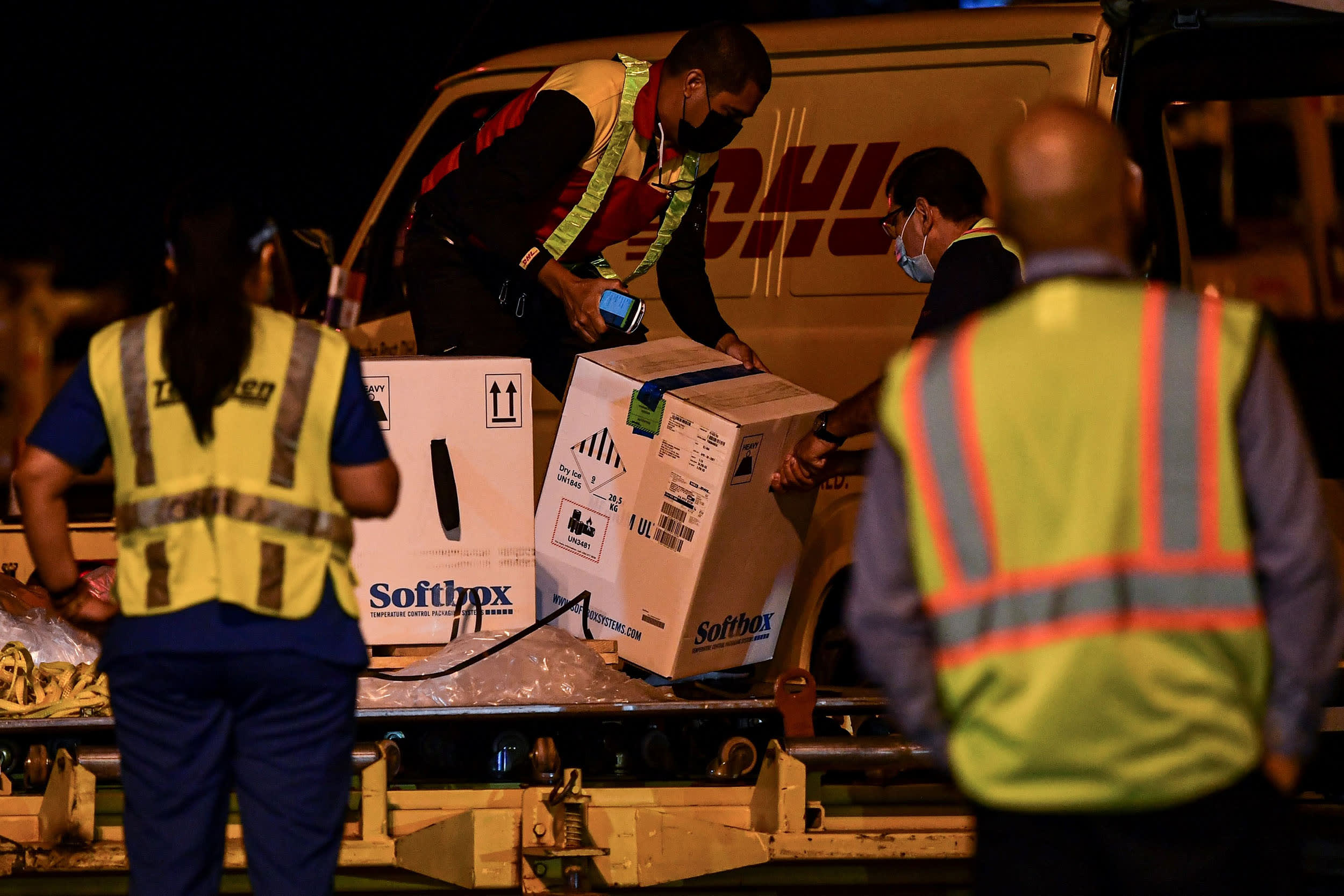 Image: Workers unload containers carrying the first shipment of the Pfizer/BioNTech Covid-19 vaccine for Panama, from a courier aircraft transporting some 12,840 doses of the vaccine into the country, at Tocumen International Airport in Panama City