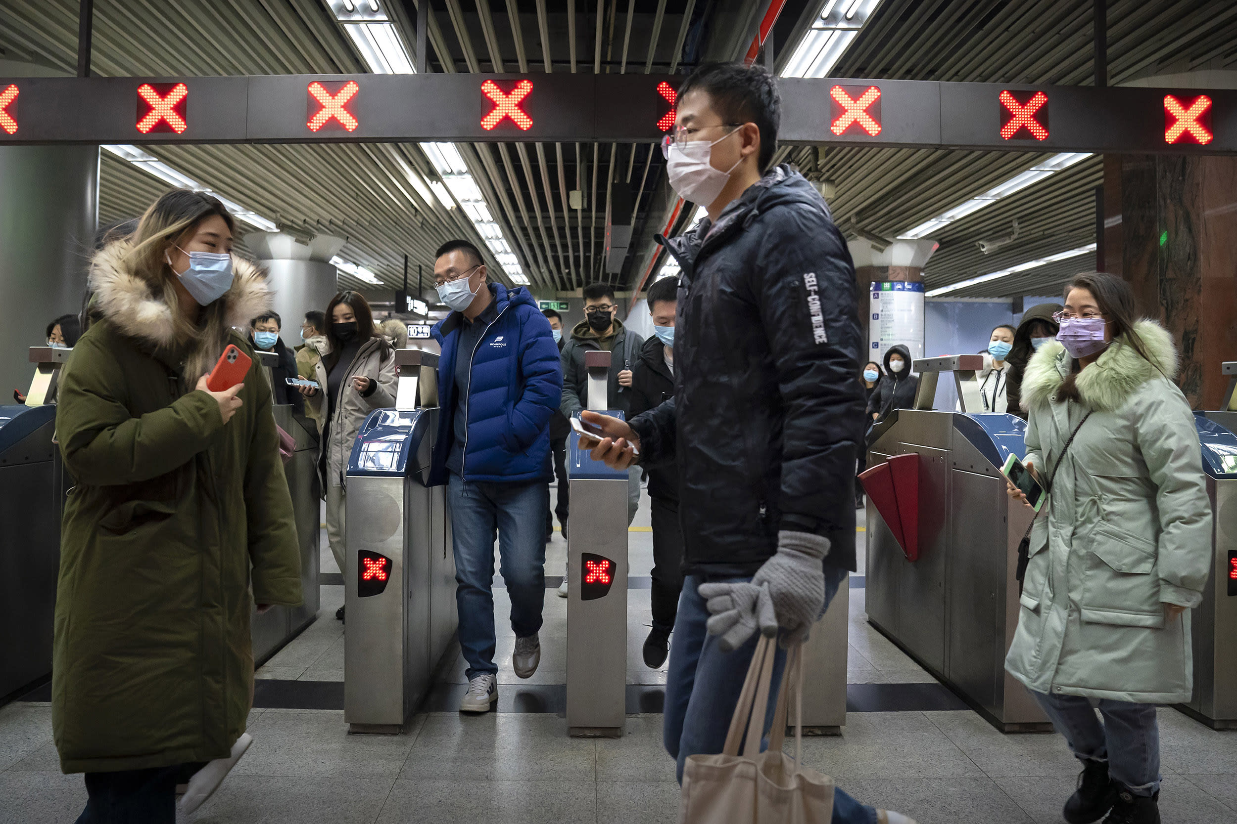 Image: People wearing face masks to protect against the spread of the coronavirus walk through a subway station in Beijing