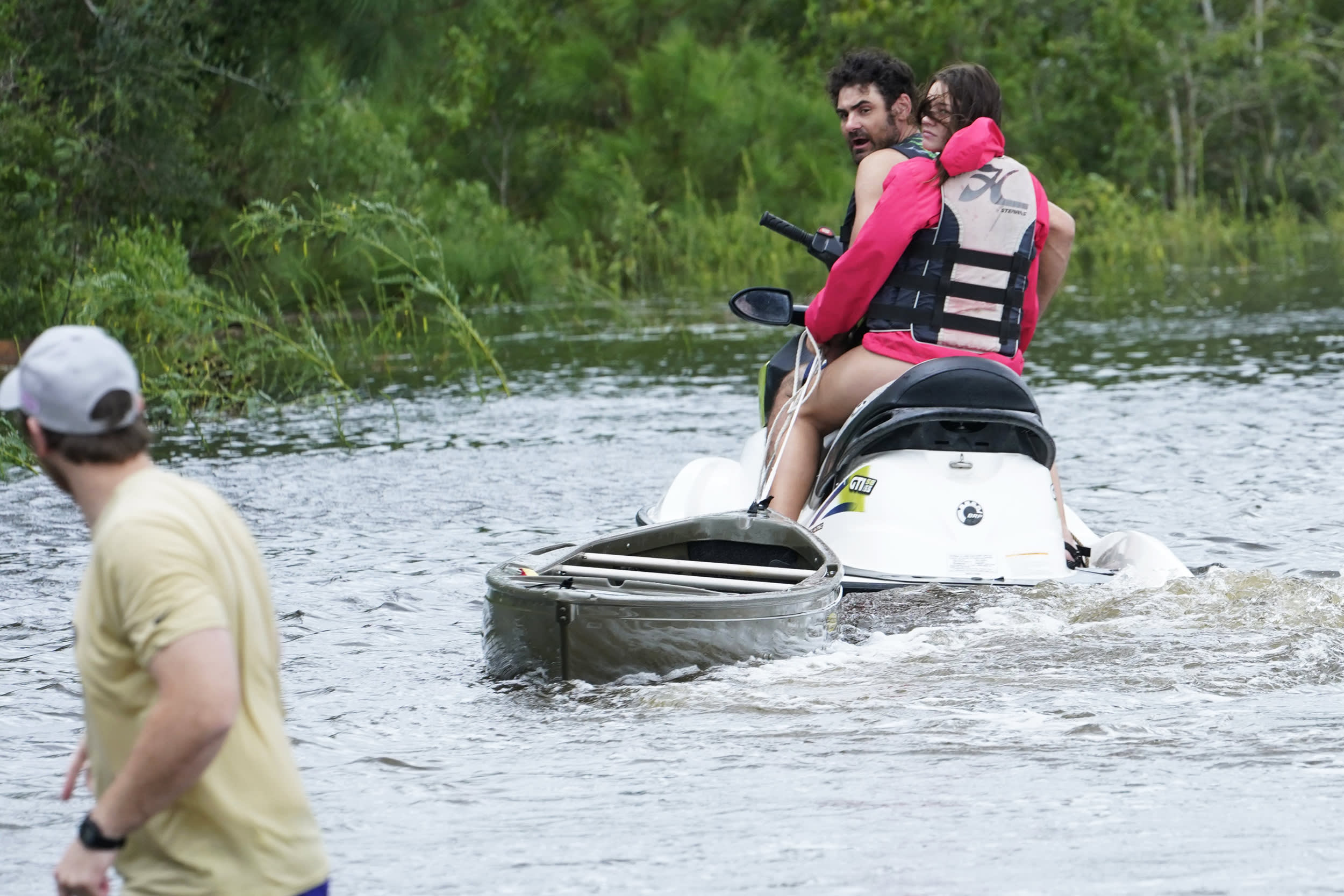 A local resident on a jet ski tows a canoe to a flooded house as the outer bands of Hurricane Ida arrive on Sunday in Bay Saint Louis, Miss.