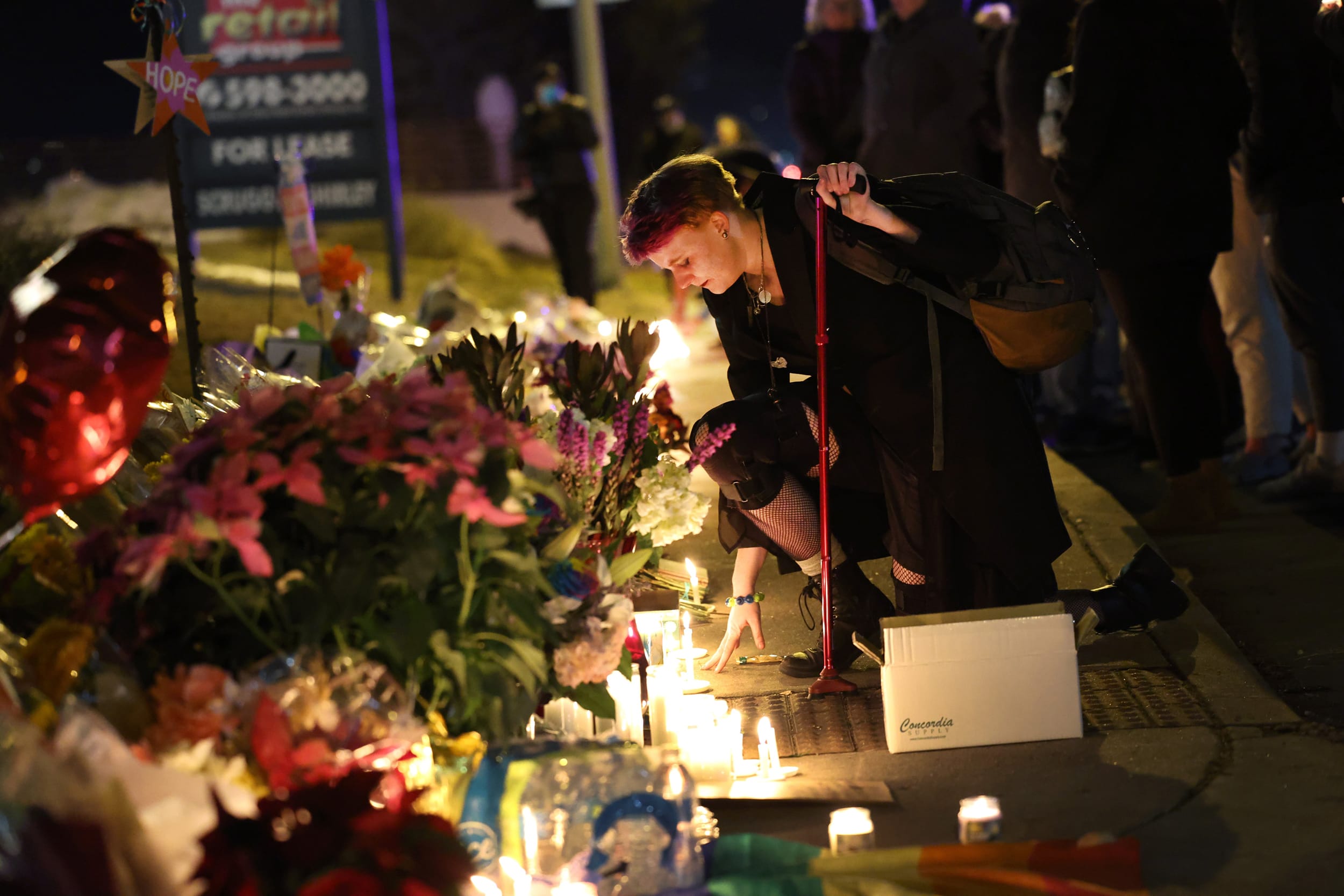 People hold a vigil at a makeshift memorial near the Club Q nightclub in Colorado Springs, Colo., on Nov. 20, 2022. 