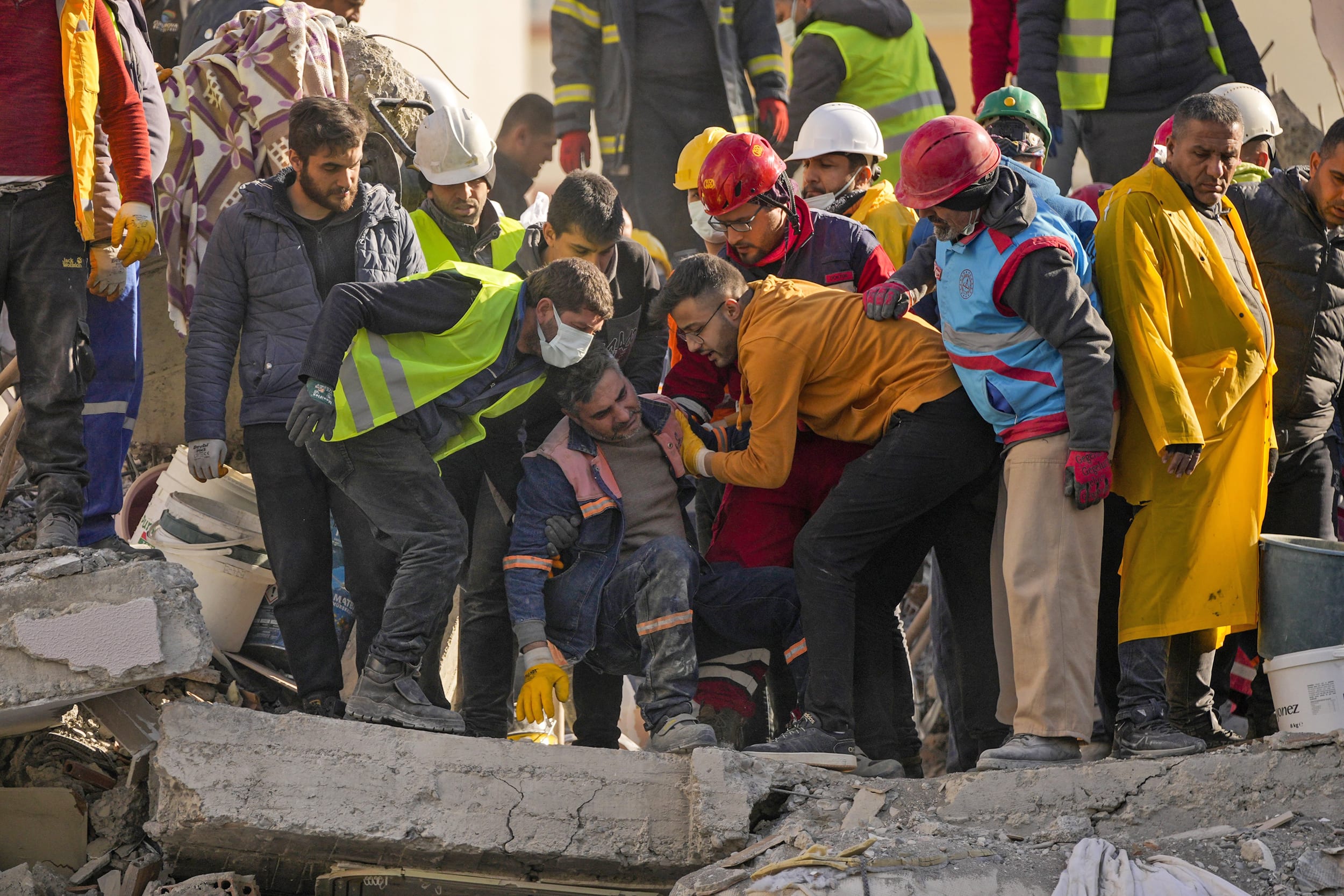 An emergency rescue team member is comforted by teammates after they found two bodies of people in a destroyed building in Adana, Turkey, on Feb. 7, 2023.