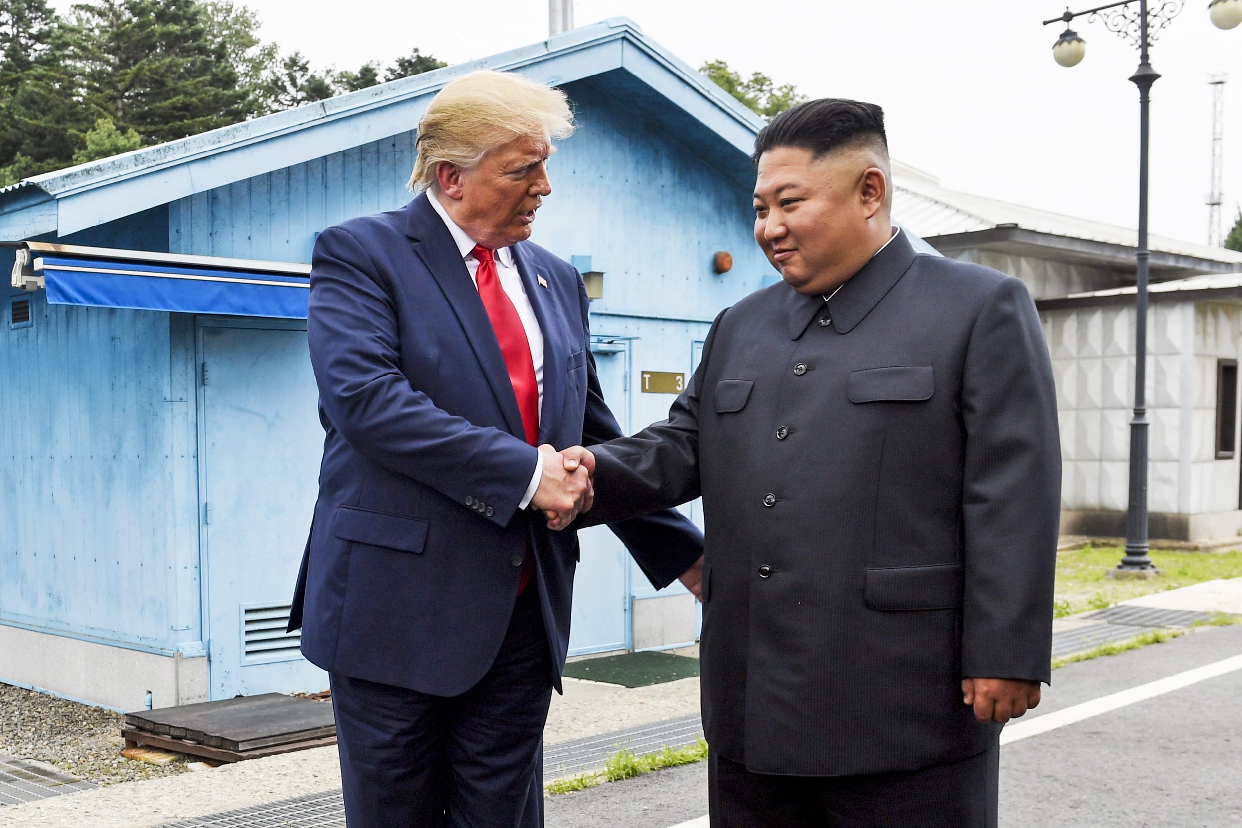 Donald Trump shakes hands with Kim Jong Un