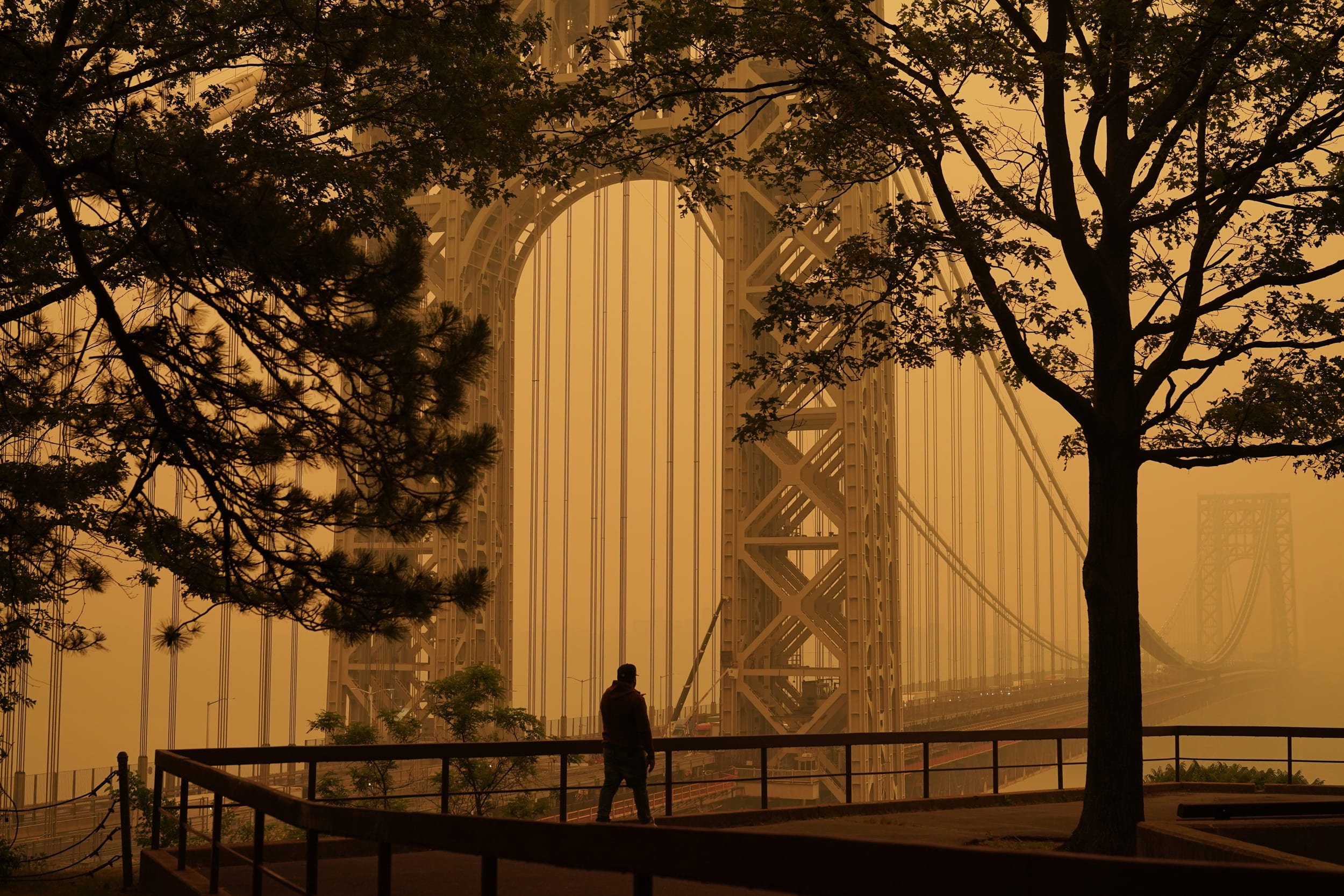 A man talks on his phone as he looks through the haze at the George Washington Bridge in Englewood Cliffs, N.J.