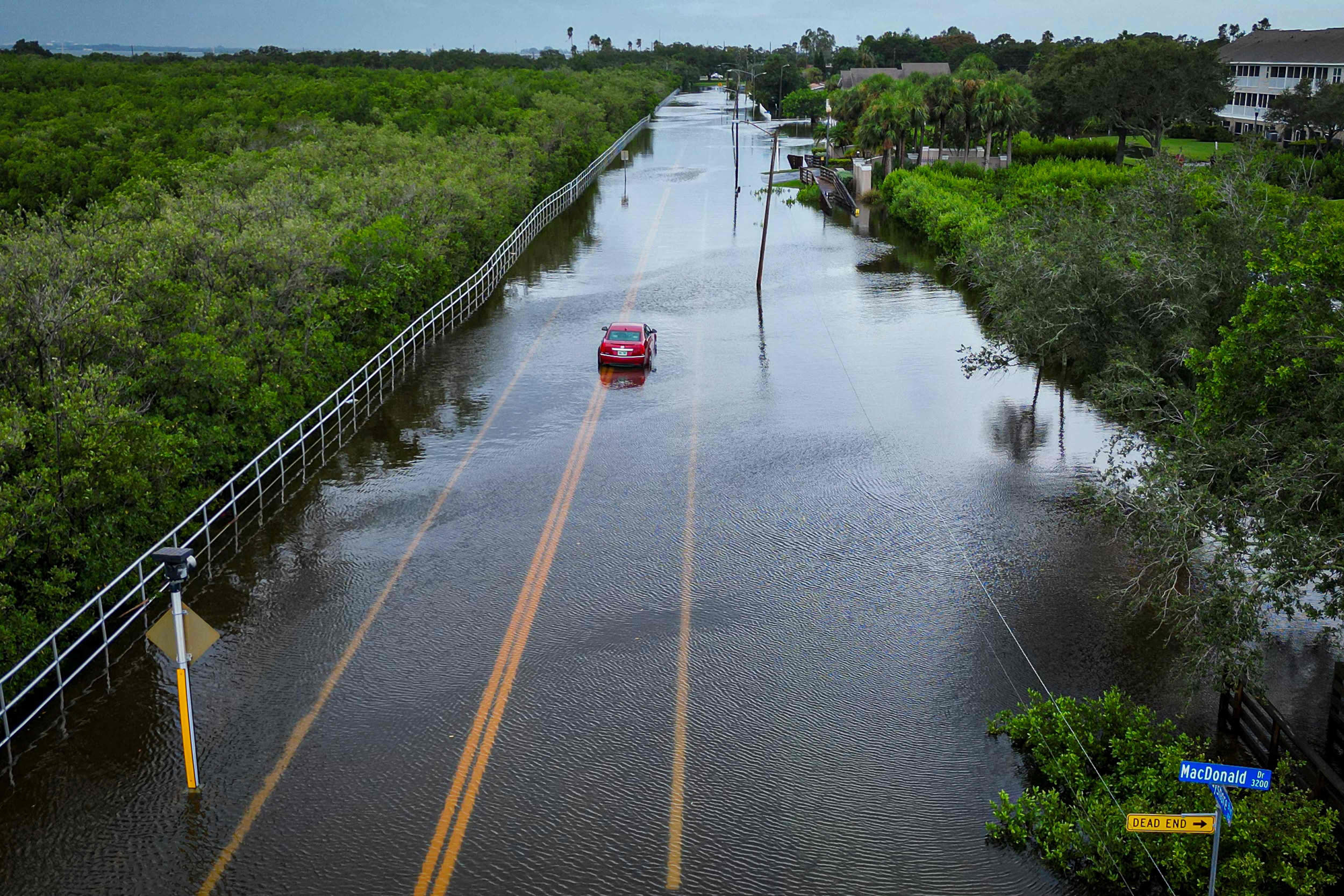 A vehicle attempts to travel on a flooded road in Tampa, Fla.