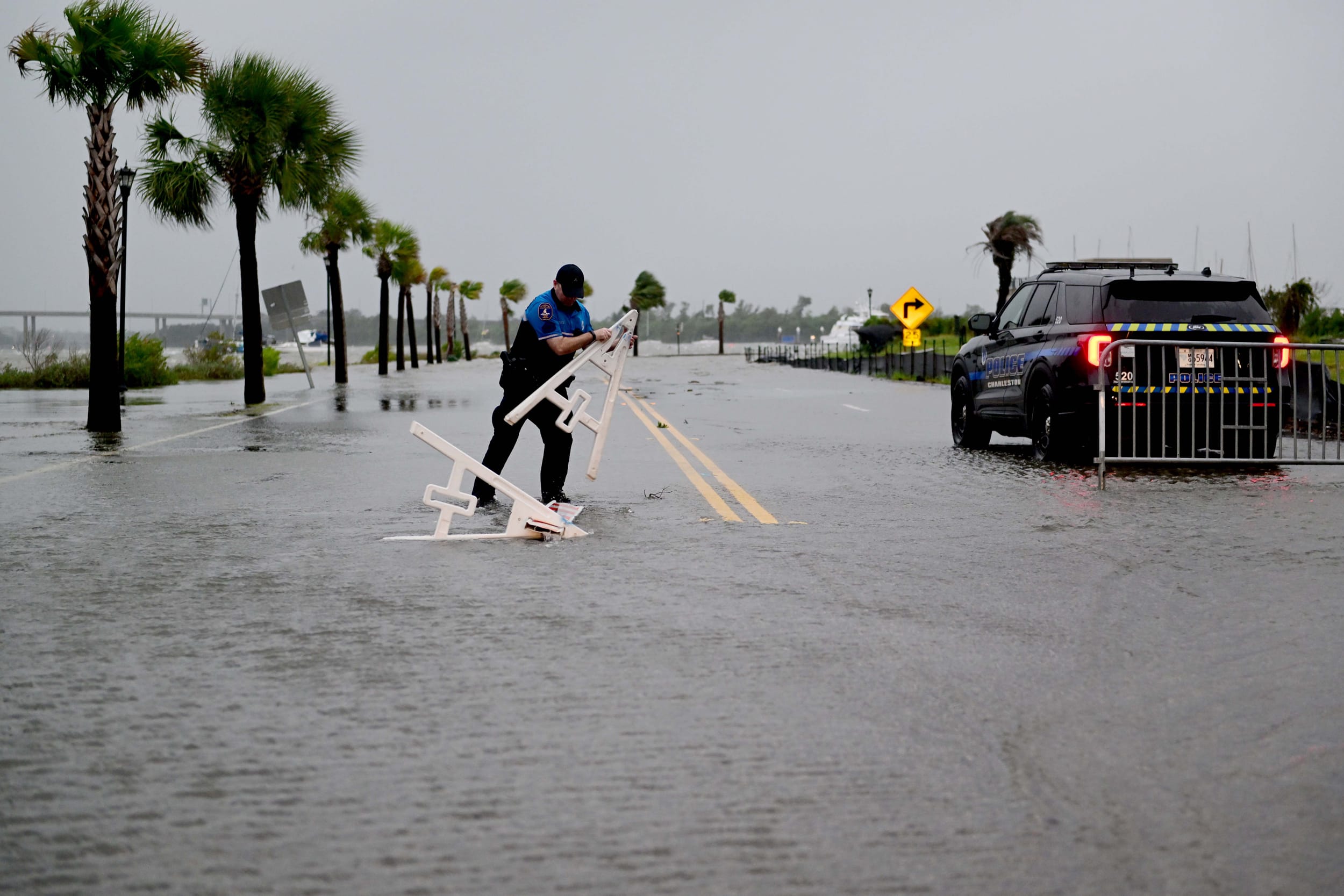 A Charleston City Police Officer picks up a road barricade in preparation to block off Lockwood Dr in Charleston, S.C., on Aug. 30, 2023