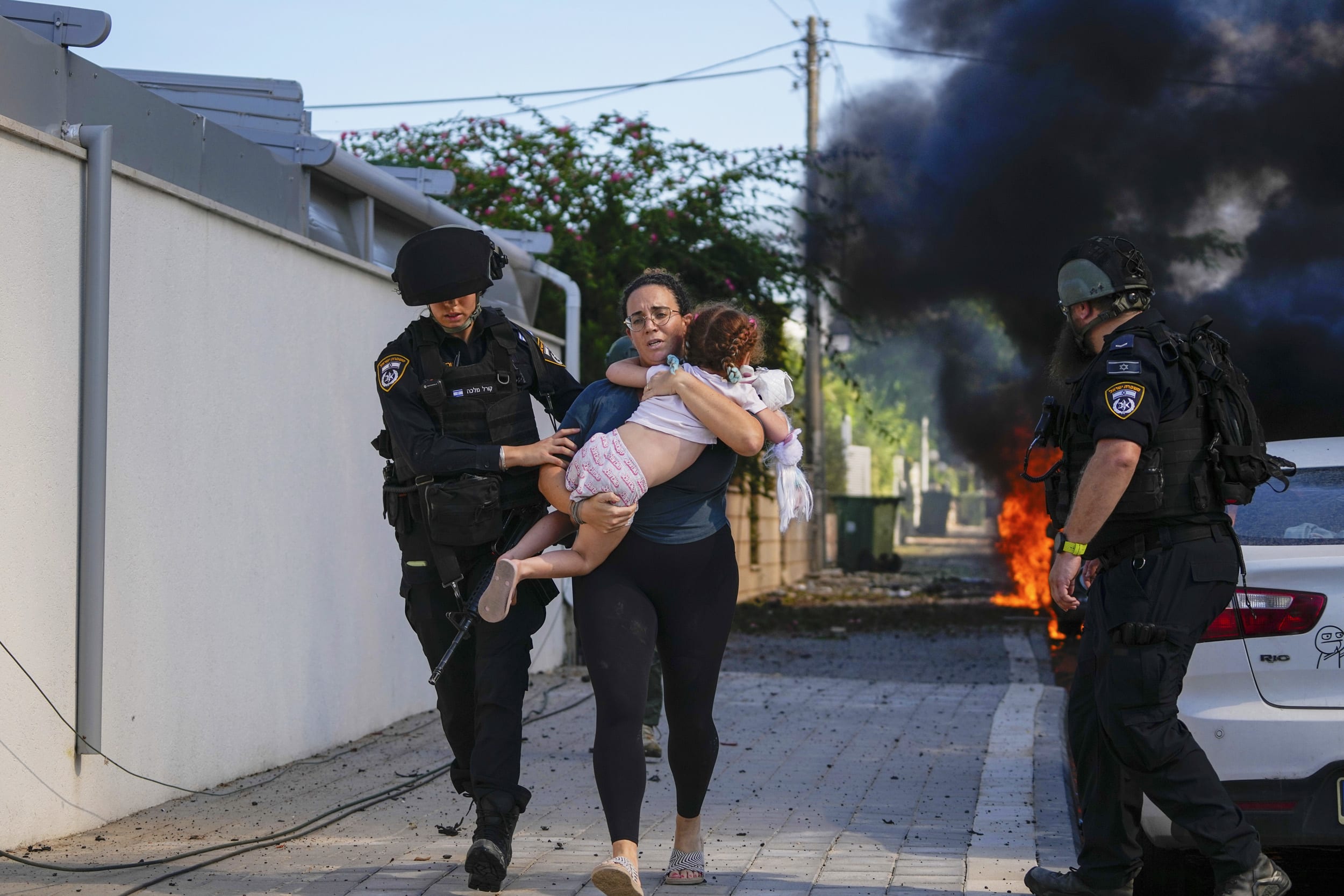 Israeli police officers evacuate a woman and a child from a site hit by a rocket fire