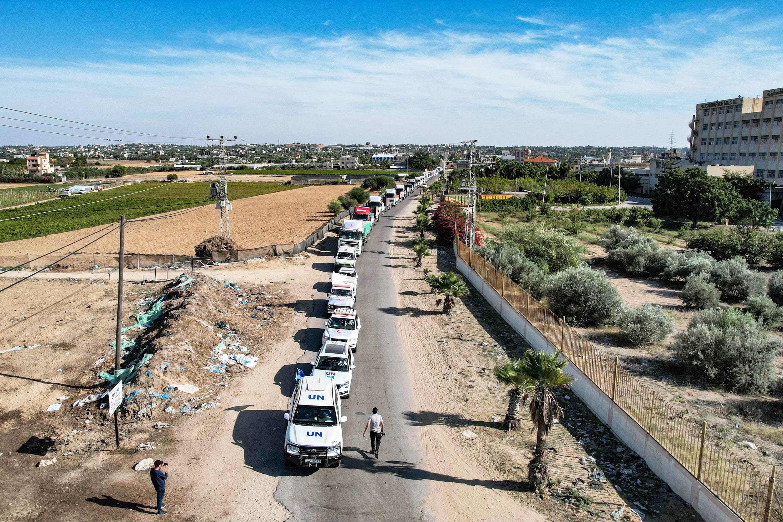 A line of humanitarian aid trucks arrive at a storage facility