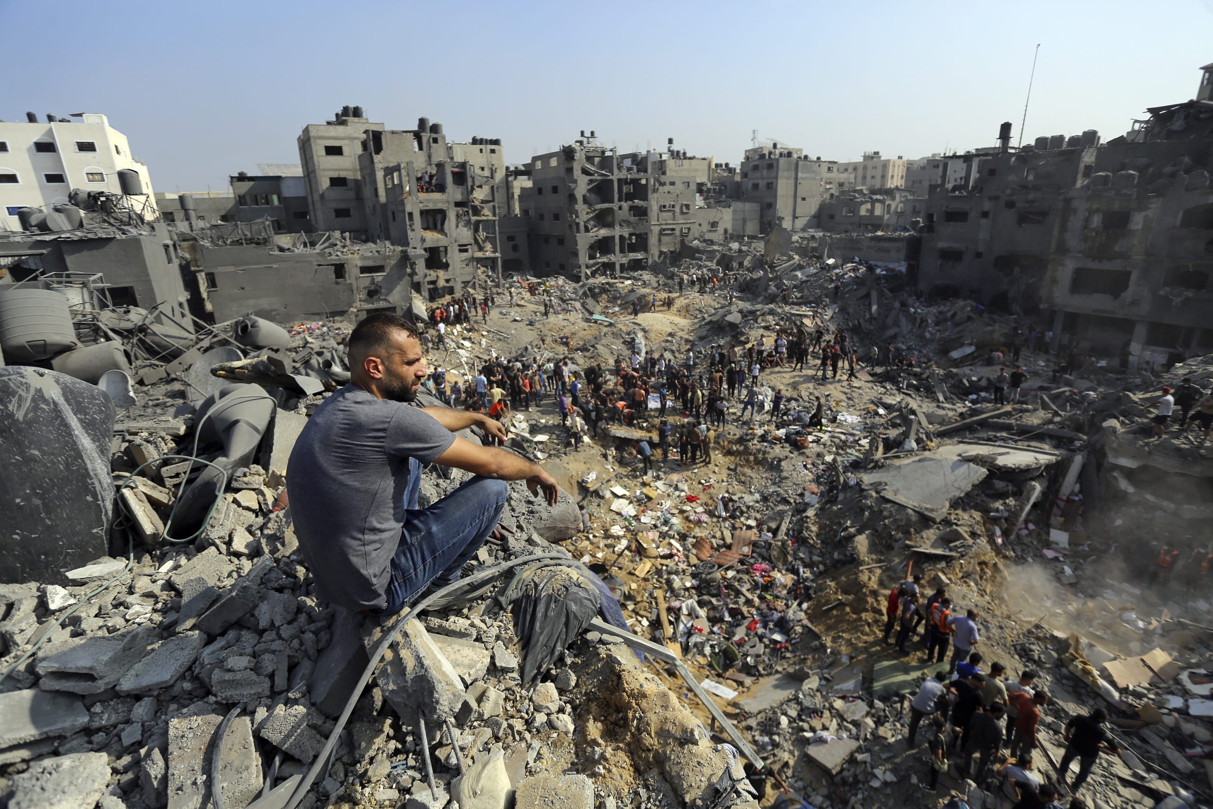A man sits on the rubble as others wander among debris of buildings that were targeted by Israeli airstrikes in Jabaliya refugee camp in northern Gaza Strip, on Nov. 1, 2023.
