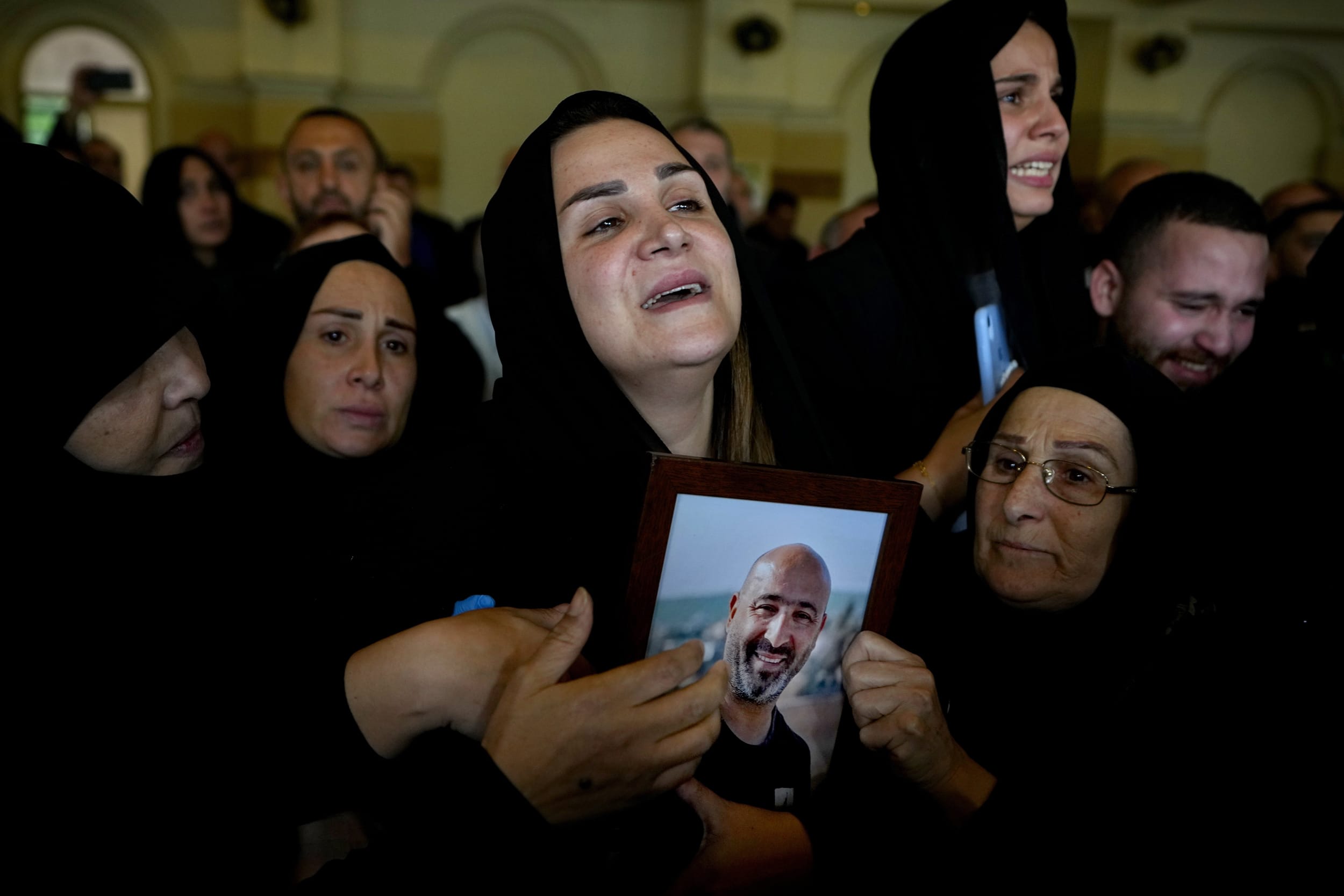Manal Jaafar holds a photo of her husband Rabih Maamari, a cameraman at pan-Arab TV network Al-Mayadeen who was killed by an Israeli strike, during his funeral procession in the southern Beirut suburb of Dahiyeh, Lebanon, on Nov. 22, 2023. Al-Mayadeen TV said Maamari and correspondent Farah Omar were killed Tuesday as they covered military activity along Lebanon's border with Israel.