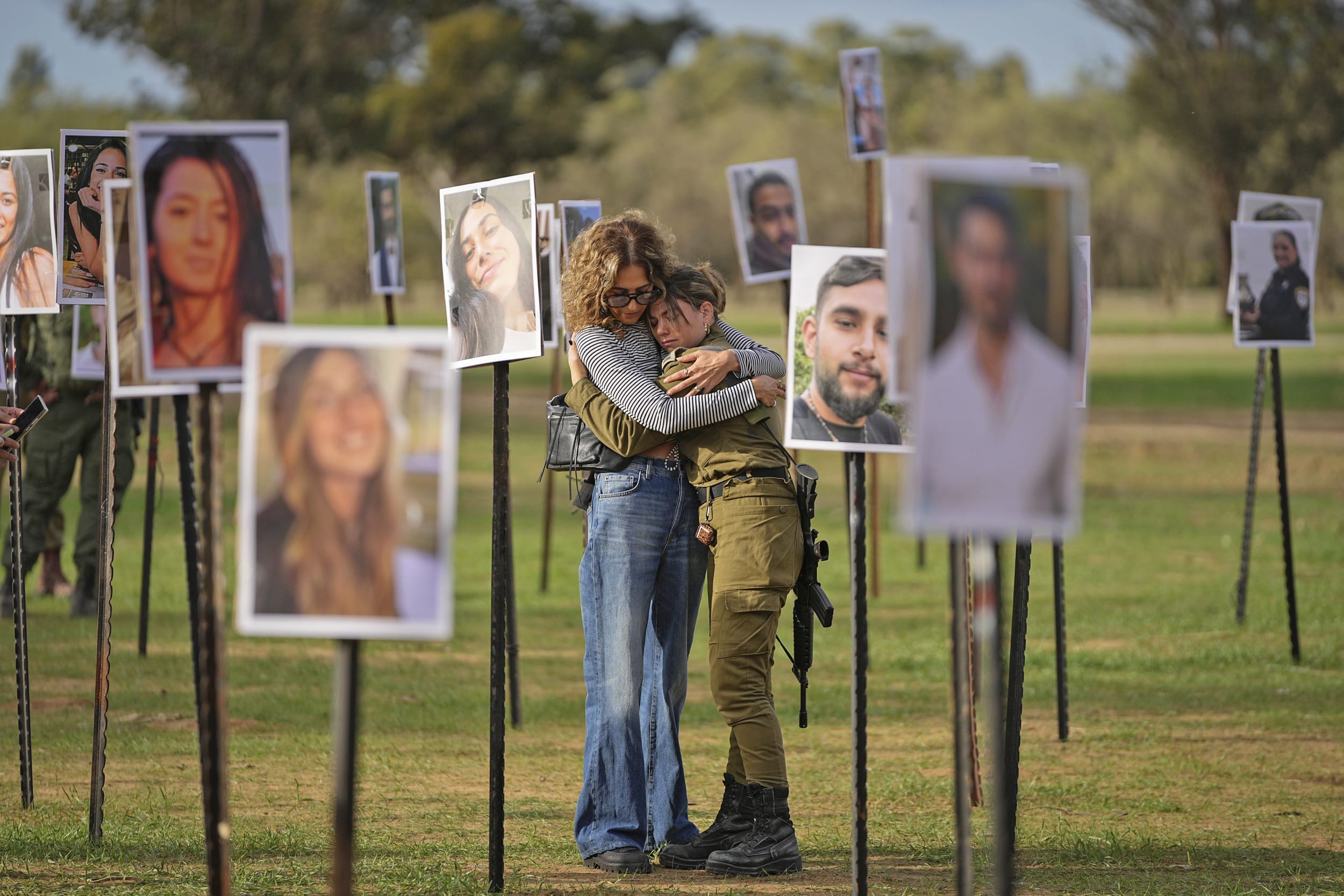Israelis embrace next to photos of victims of the attack on the Nova music festival displayed at the site, near kibbutz Re'im, on Tuesday, Nov. 28, 2023.