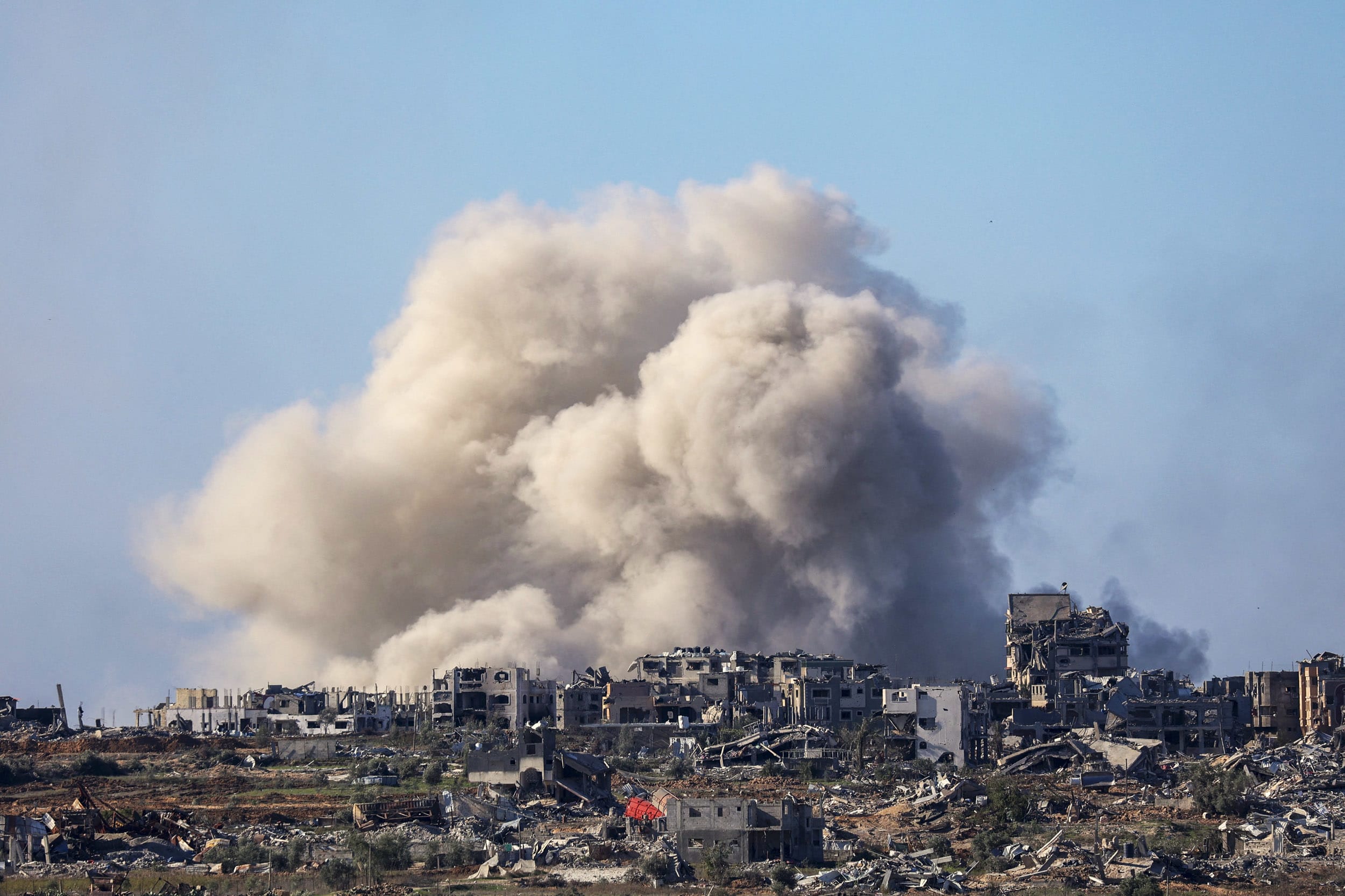 A plume of smoke forms over a skyline of destroyed buildings in Gaza.