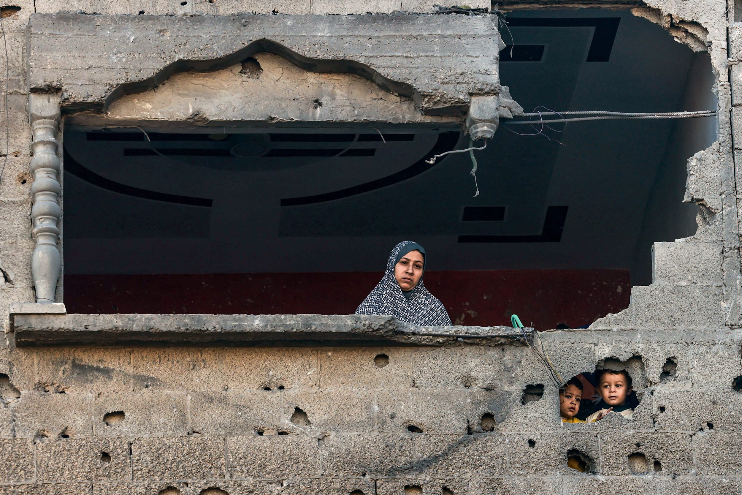 A Palestinian woman and children look out from a damaged building Rafah, southern Gaza, on Dec. 15, 2023.
