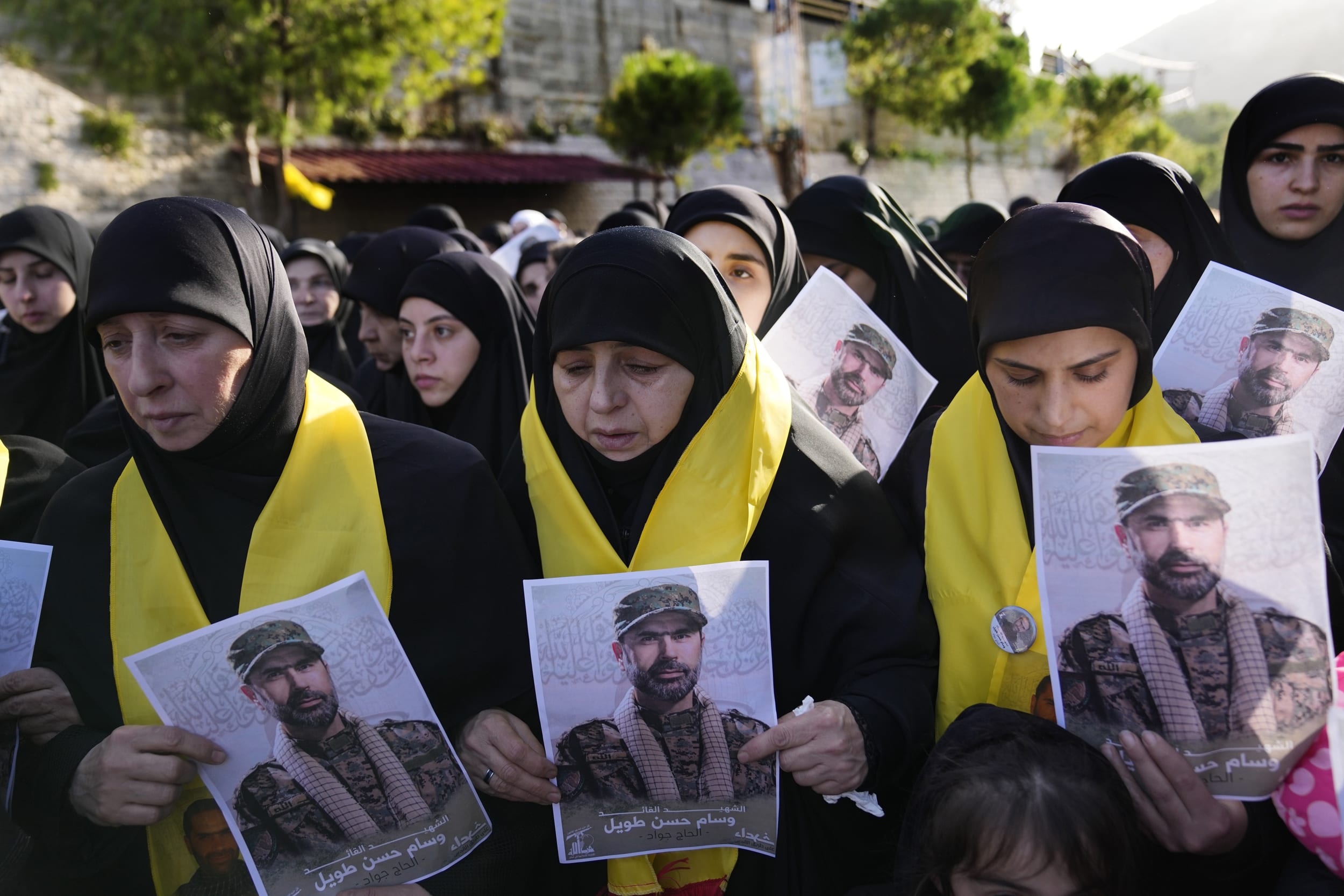 Mourners hold portraits of senior Hezbollah commander Wissam Tawil during his funeral procession in the village of Khirbet Selm, Lebanon