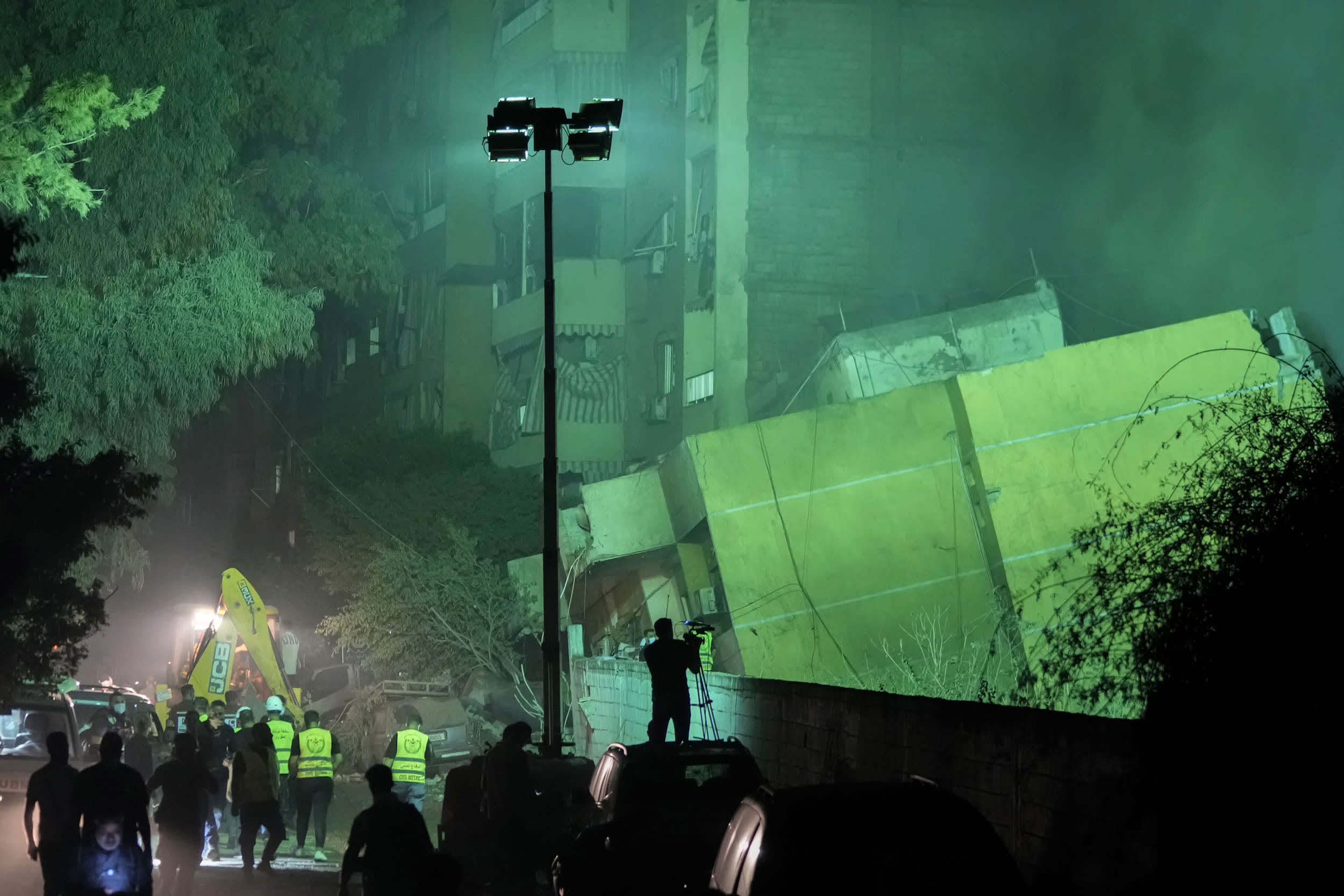 Image: A collapsed building and emergency workers.