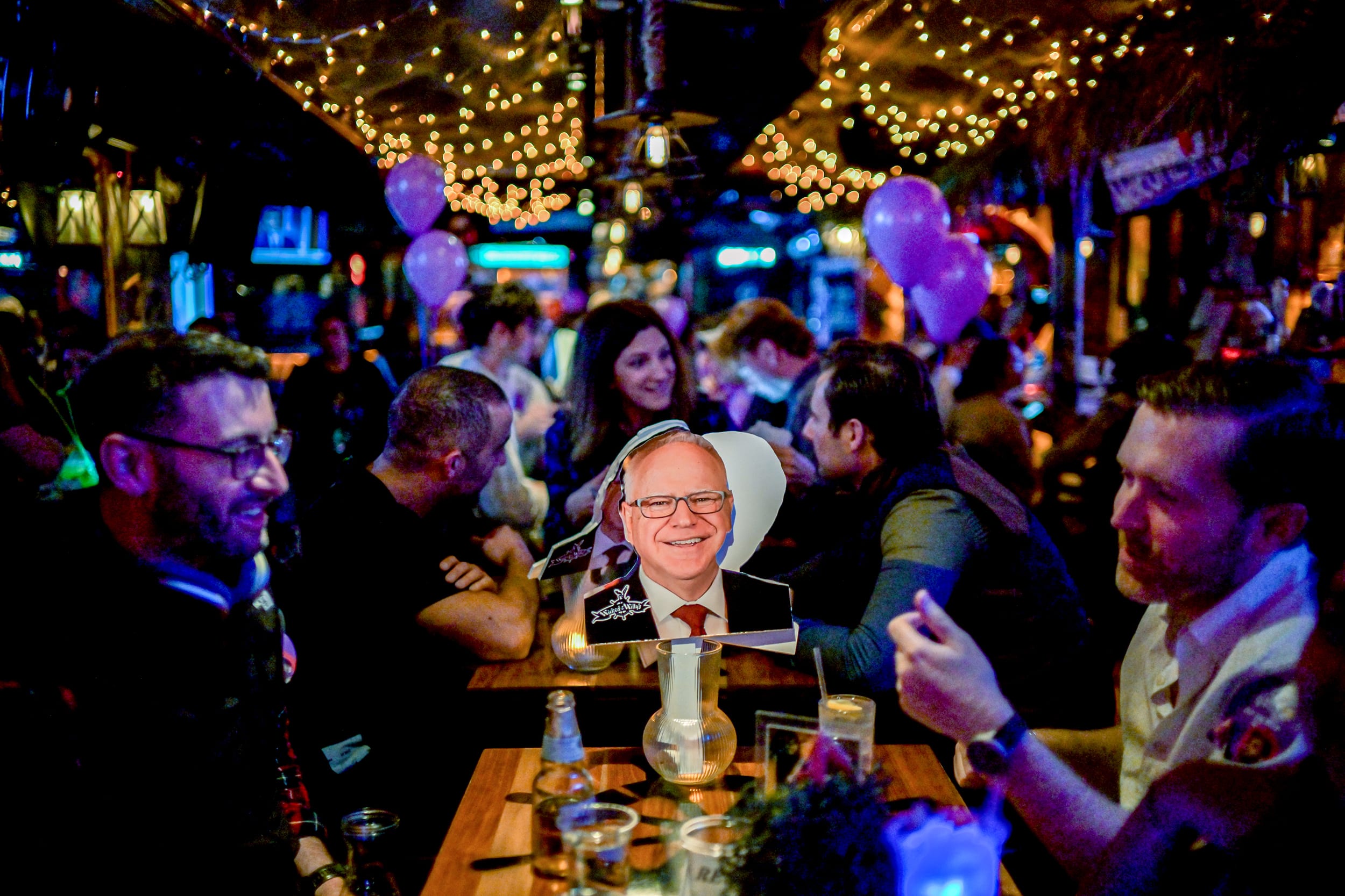 Attendees sit near a cutout image of Tim Walz