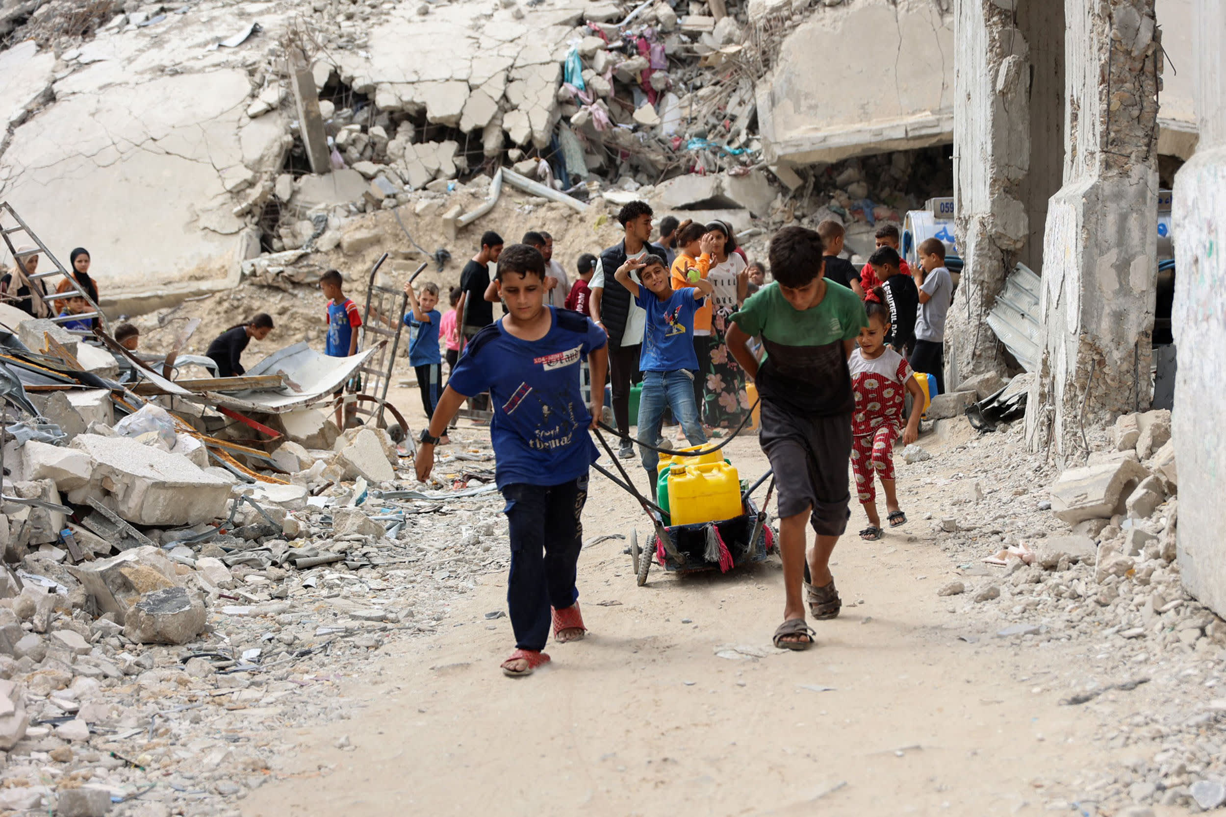 Displaced Palestinian boys pull containers to ferry water from a distribution point in the Shujaiya neighborhood of Gaza City on Oct. 7, 2024.