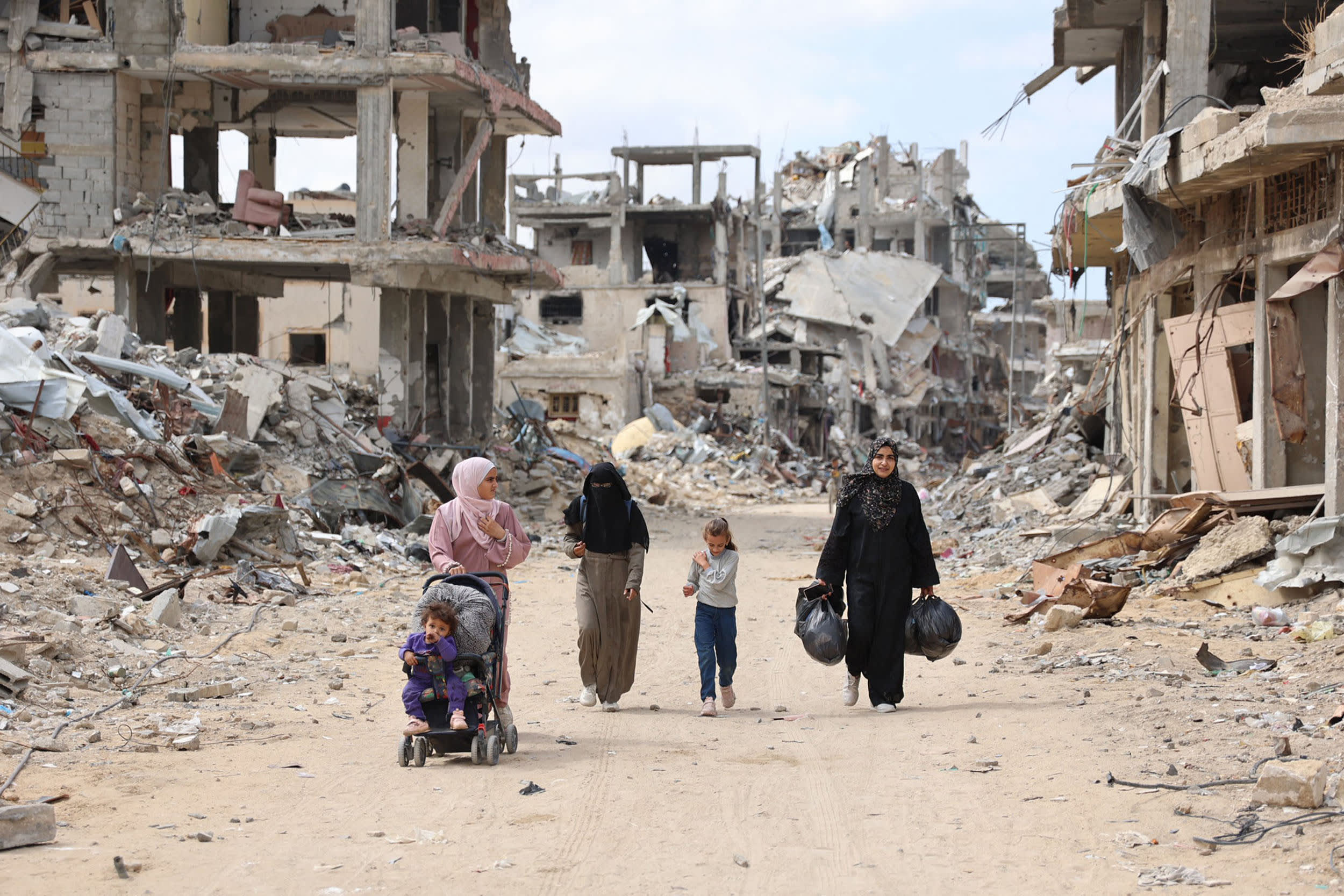 Palestinians walk on a road lined with destroyed buildings in the Shujaiya neighborhood of Gaza City on Oct. 7, 2024.