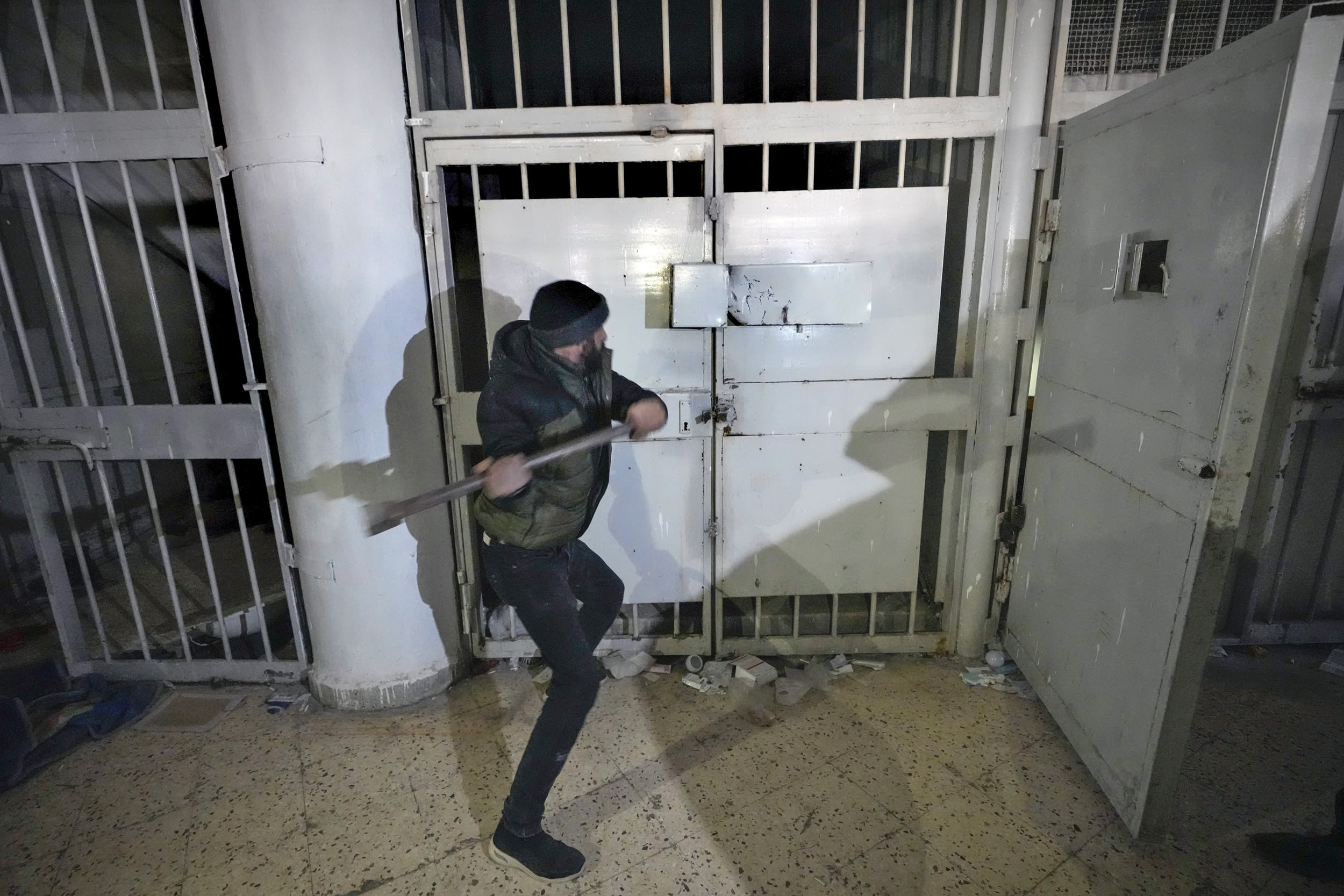 A man breaks the lock of a cell in the infamous Saydnaya military prison, just north of Damascus, Syria, Monday, Dec. 9, 2024. 